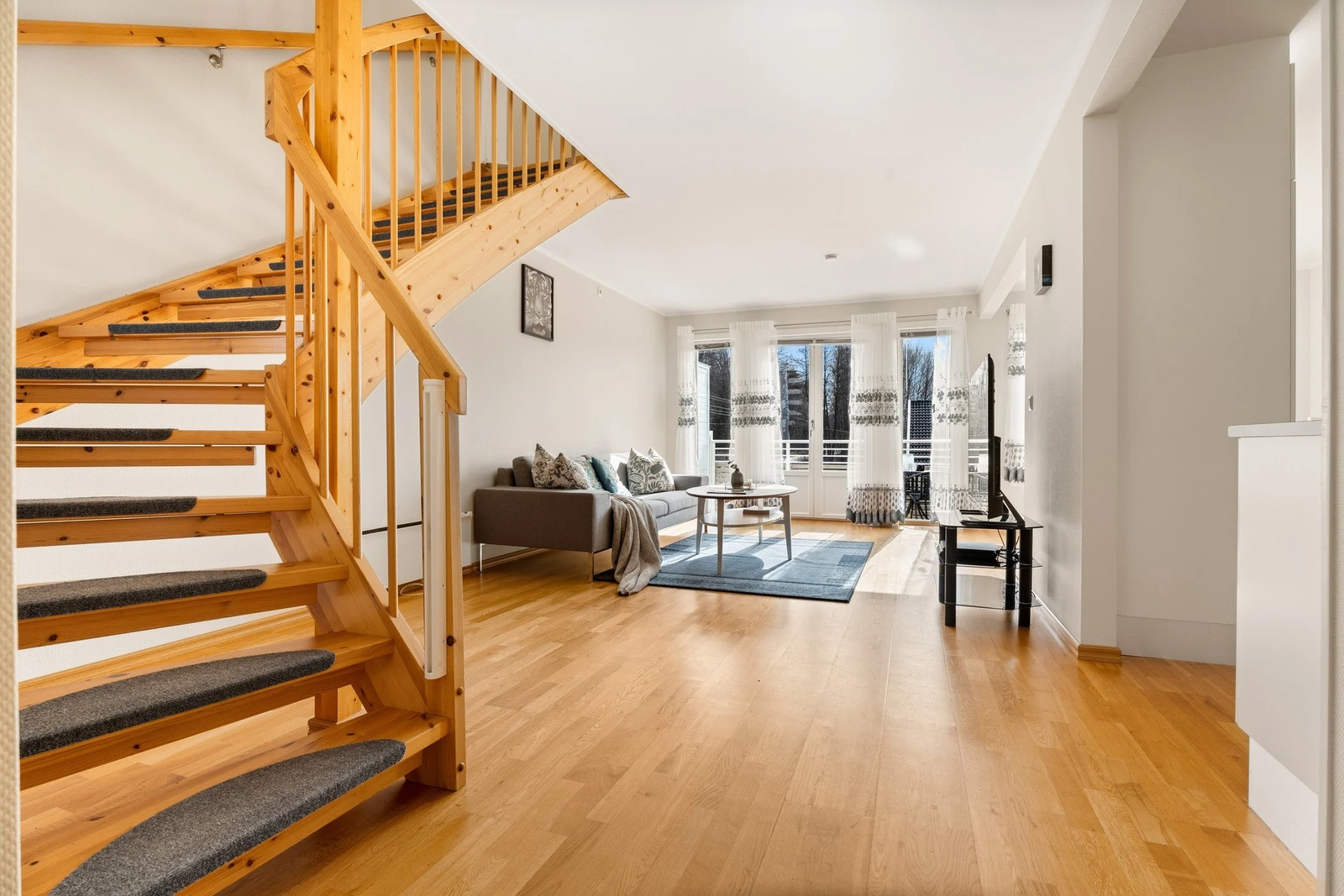 Lys og romslig stue med store vinduer som slipper inn mye naturlig lys. Galleribilde