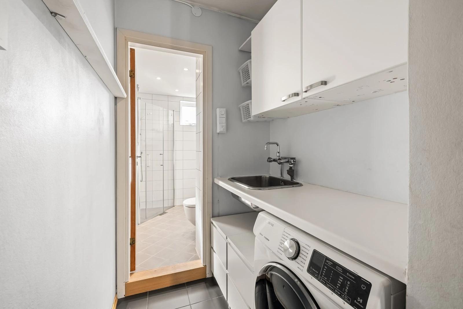 Moderne baderomsinnredning med opplegg for vaskemaskin.