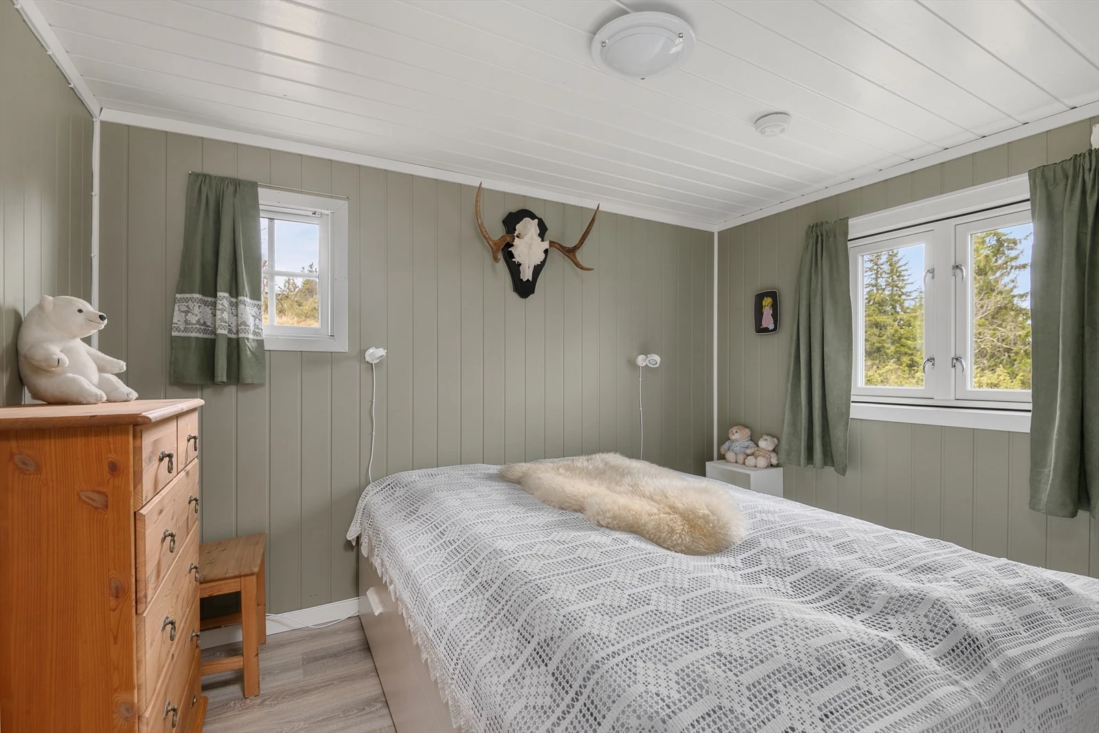 Romslig hovedsoverom med vegger malt i delikat og tidløs grønntone. Plass til oppbevaringsmøbel. Galleribilde