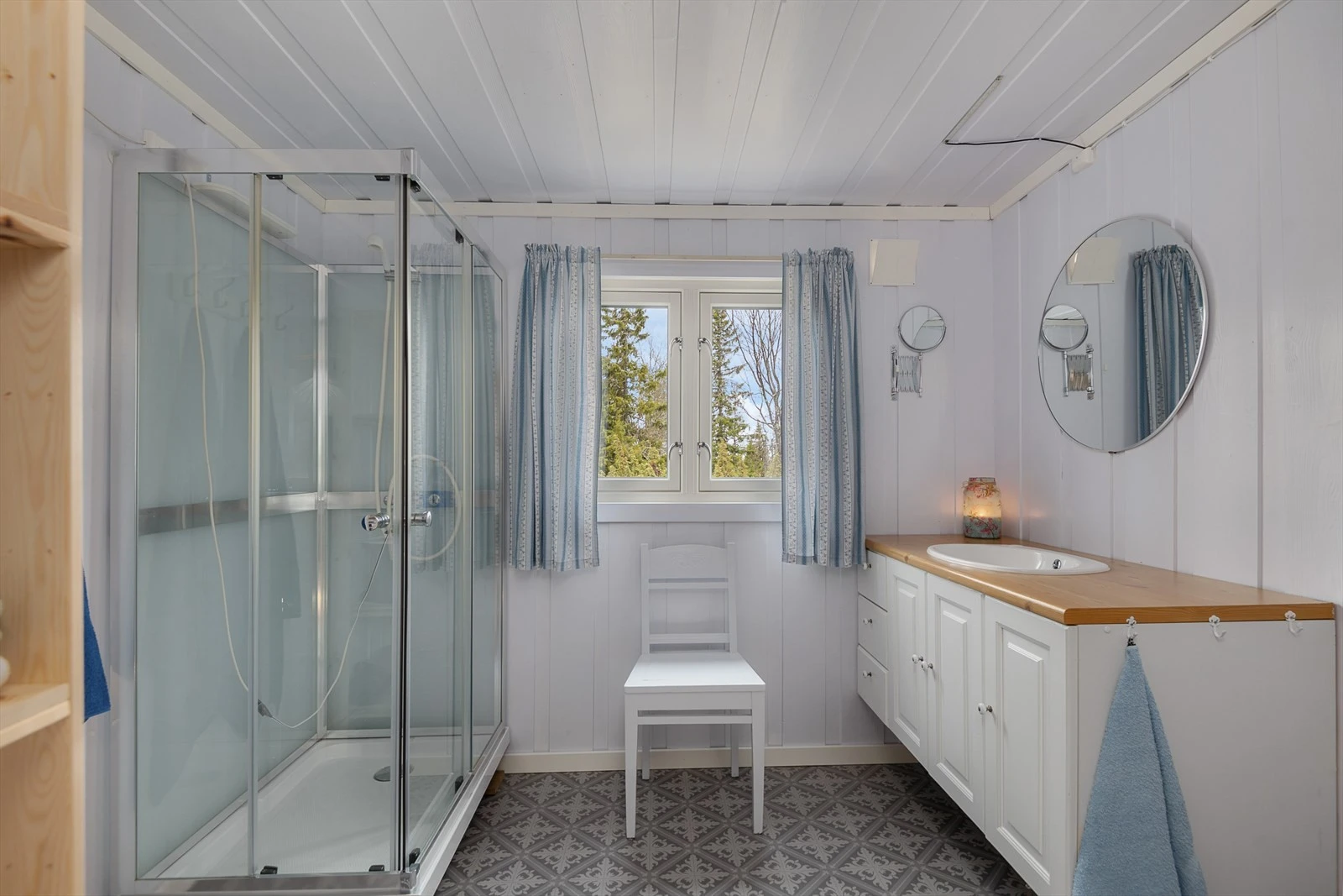 Pent og praktisk baderom med hyttedusj og servantinnredning. Belegg på gulv og malte vegger. Galleribilde