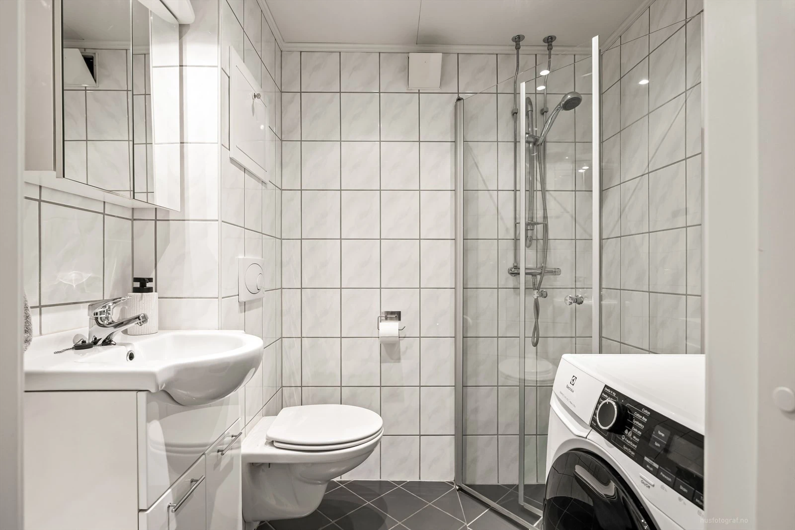 Moderne baderomsinnredning med opplegg for vaskemaskin.