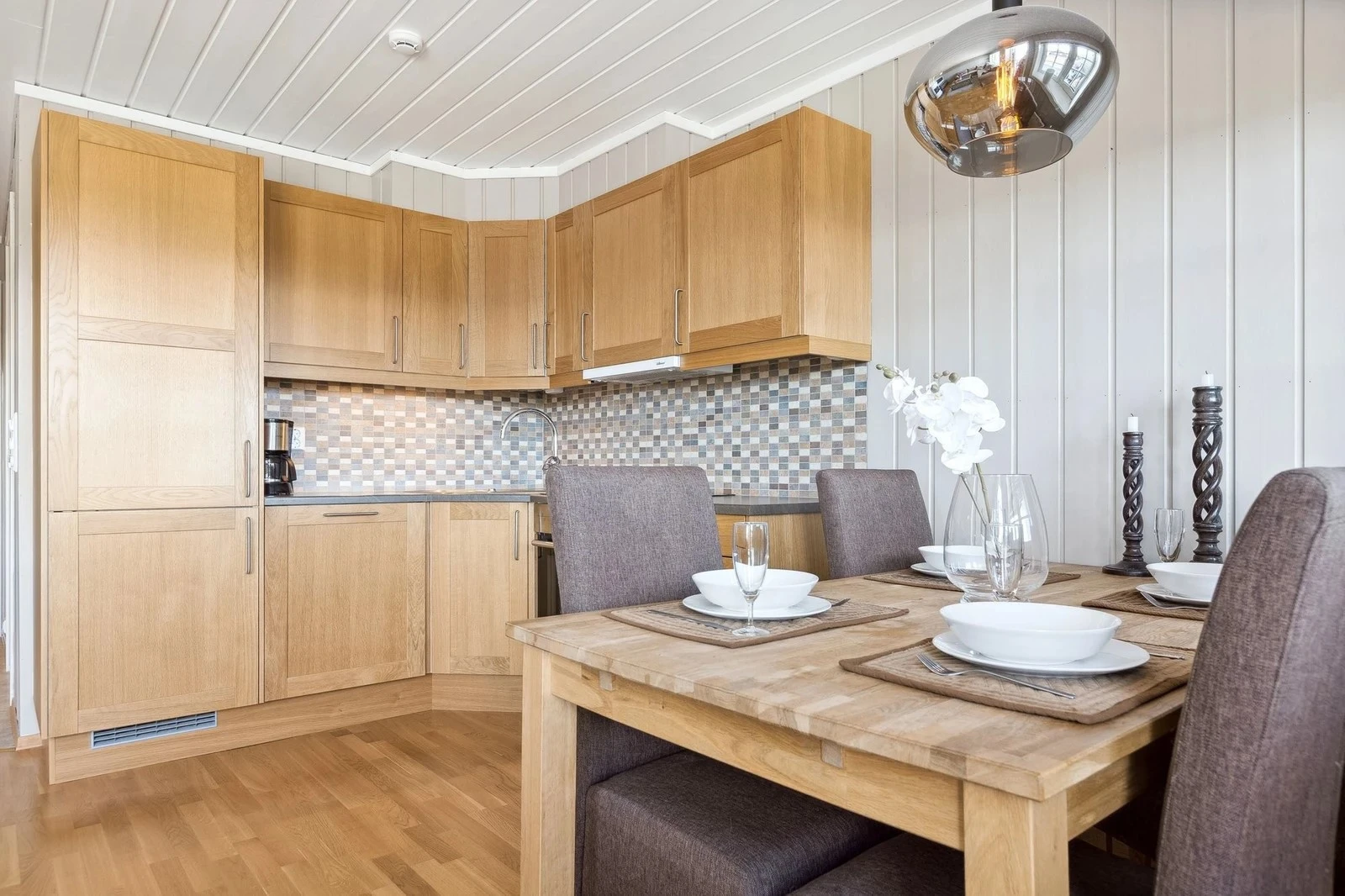 Kjøkkenet er utstyrt med integrerte hvitevarer som platetopp, stekeovn, kjøle-/fryseskap og oppvaskmaskin, i tillegg til en praktisk nedfelt vaskekum i stål Galleribilde