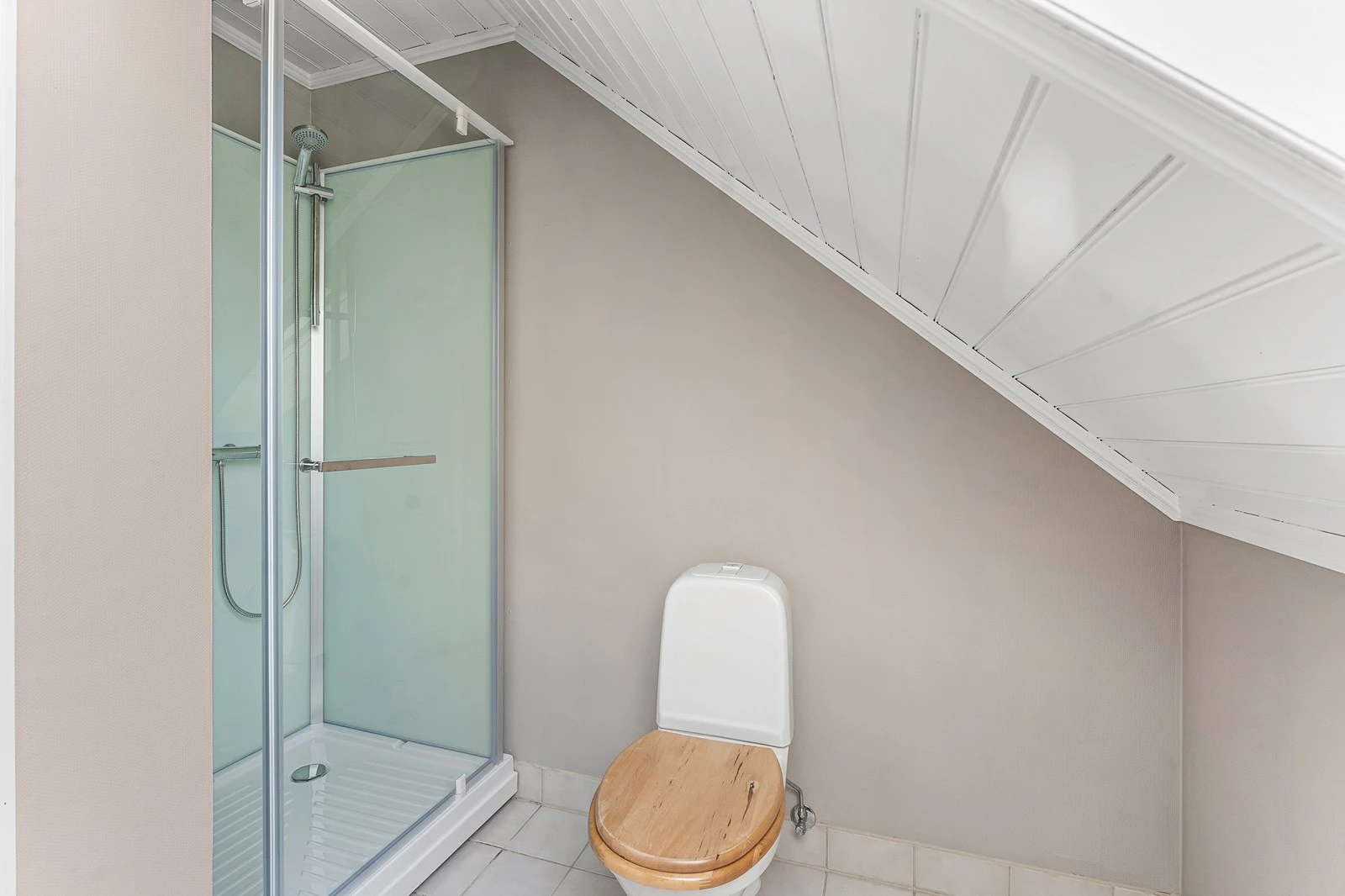 Badet er utstyrt med en enkel vask, et gulvstående toalett, og frittstående dusjkabinett. Galleribilde