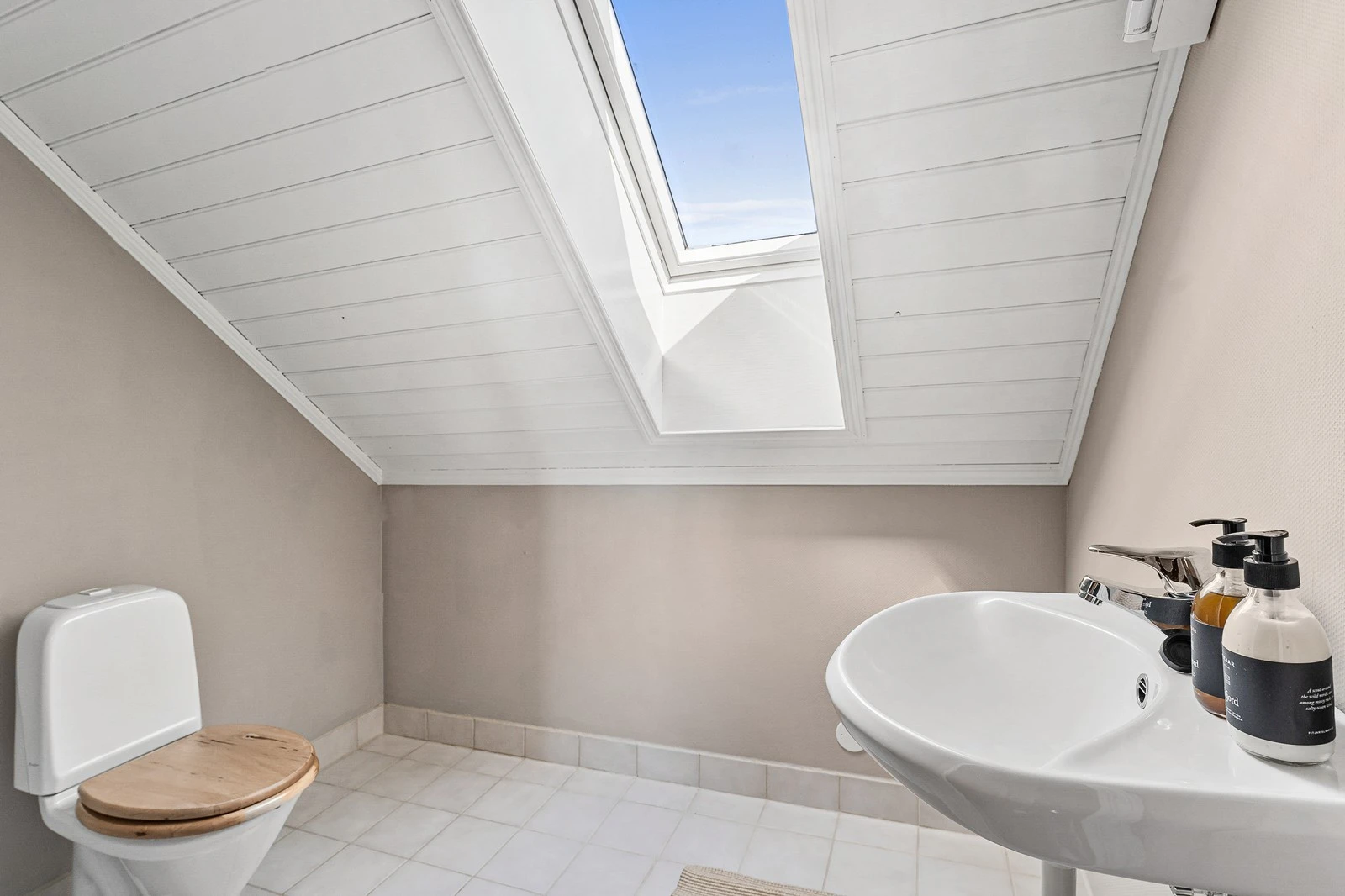 Badet på loftet har flislagt gulv, veggene er dekket med tapetserte plater, og himlingen består av malt panel. Galleribilde