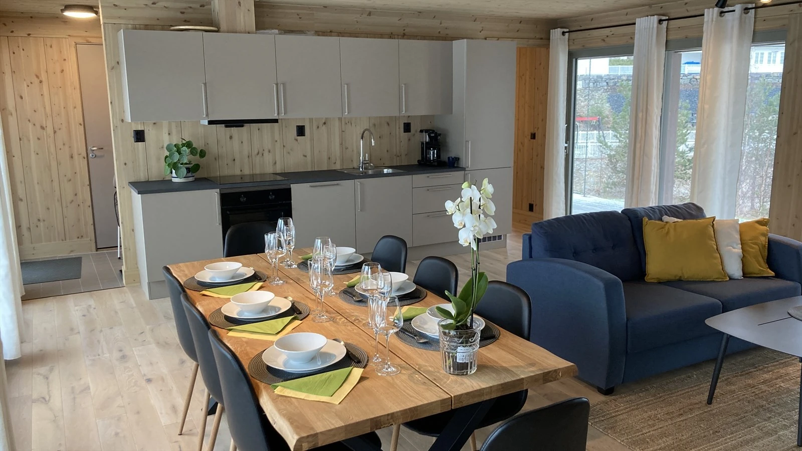 Koselig stue med åpen kjøkkenløsning. Store skyvedører på begge sider av rommet kan åpnes mot hage og terrasse. Galleribilde