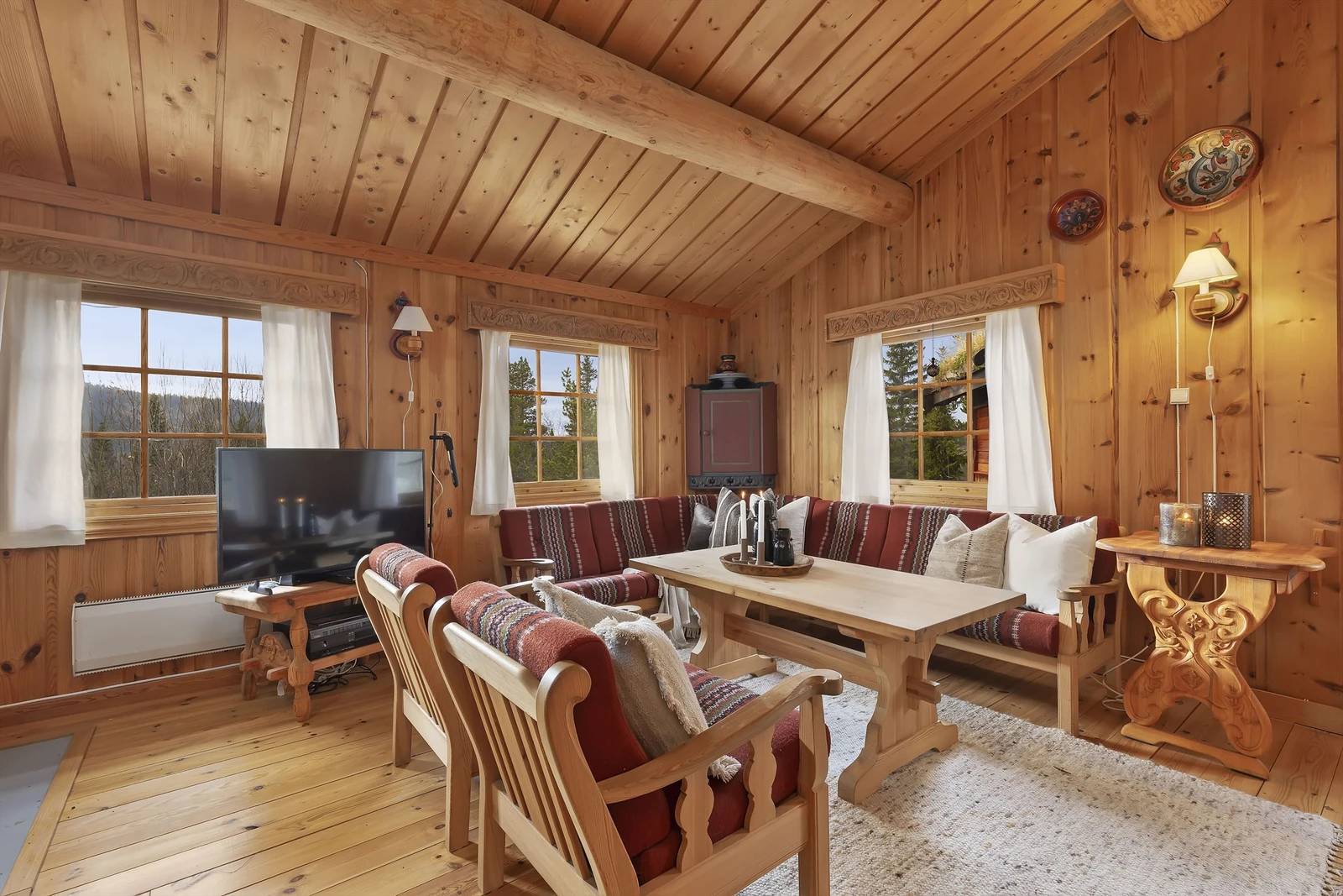 Stue med luftig skråtak og synlige rundstokker i taket Galleribilde