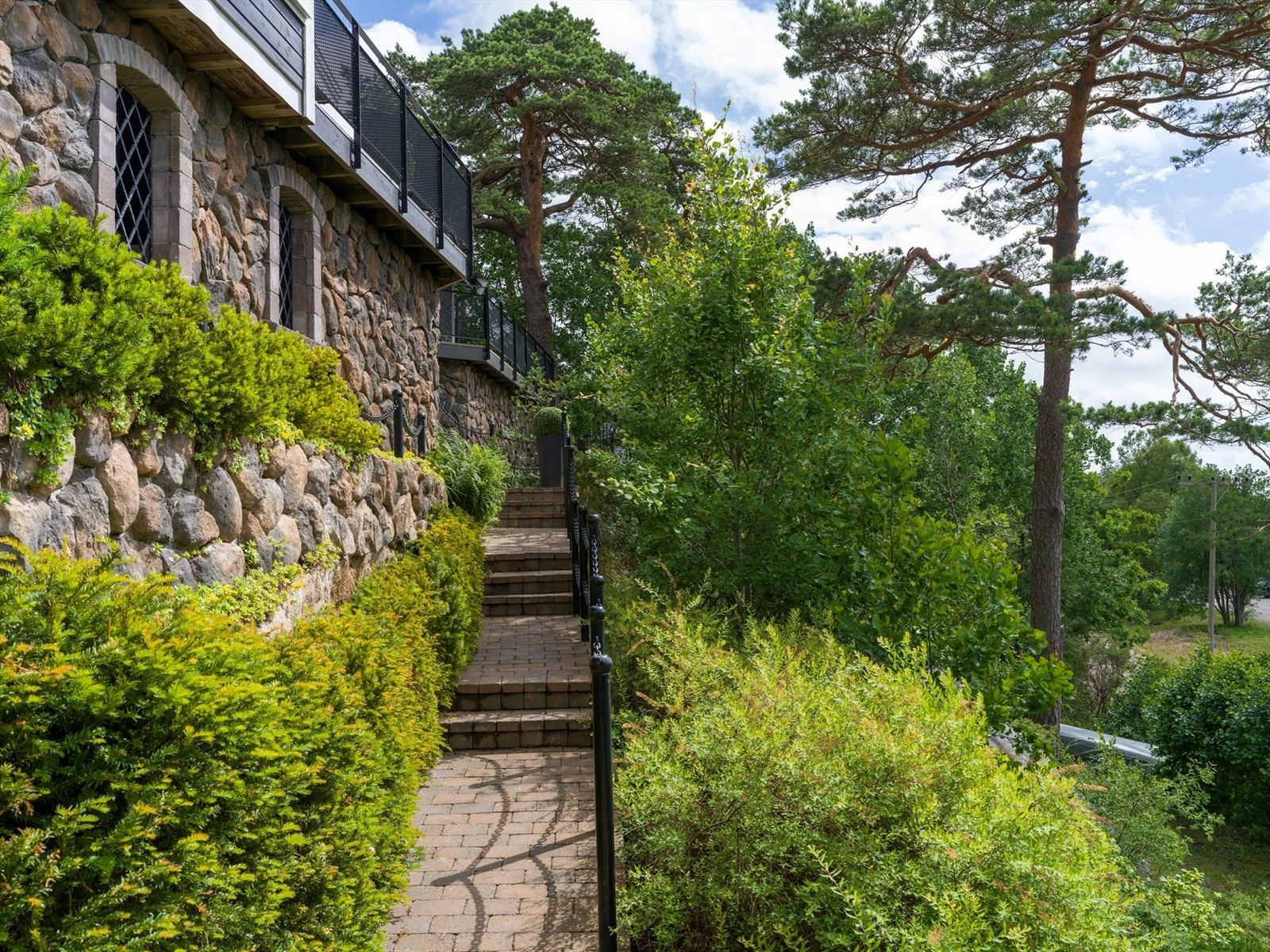 Gangvei og trapper av belegningsstein leder mellom hytta og biloppstillingsplass nedenfor. Galleribilde