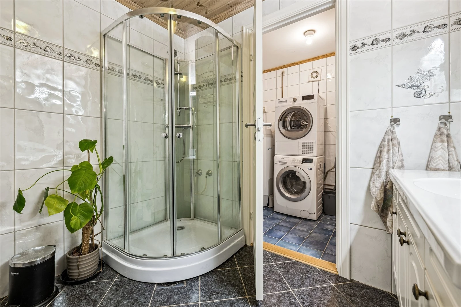 Moderne baderomsinnredning på badet og opplegg for vaskemaskin og tørketrommel i separat vaskerom.