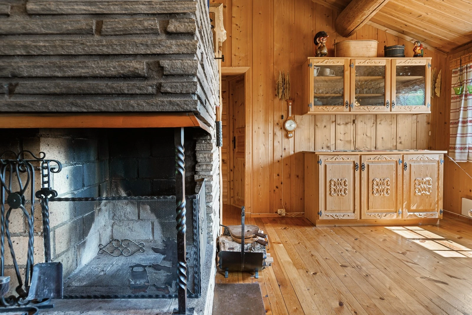 Åpen plassmurt peis i stue forblendet med skiferstav og bruddheller på pipe. Galleribilde