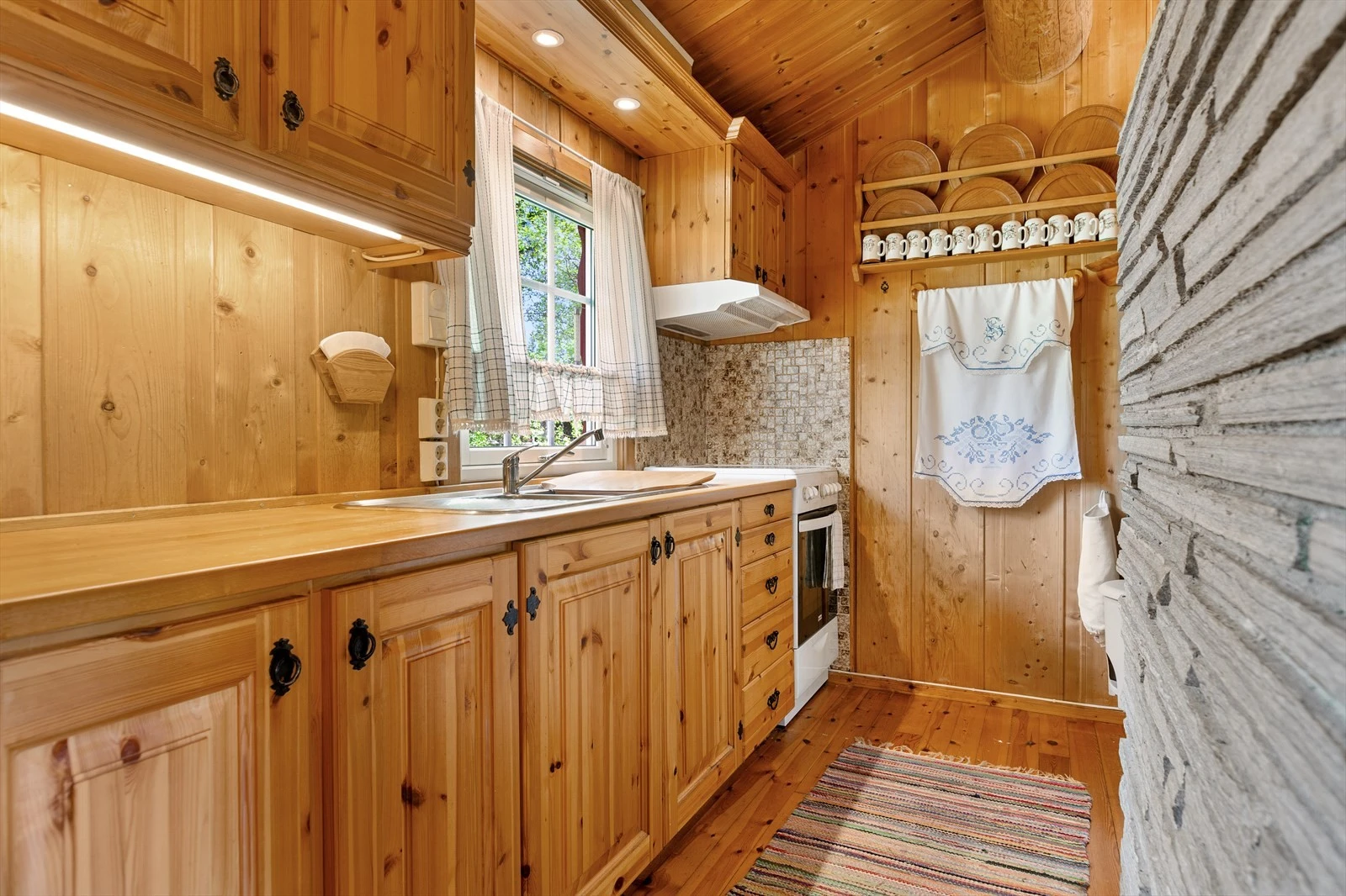 Kjøkkeninnredning i heltre med over-og underskap, heltre benkeplate og oppvaskkum med kran av stål. Galleribilde