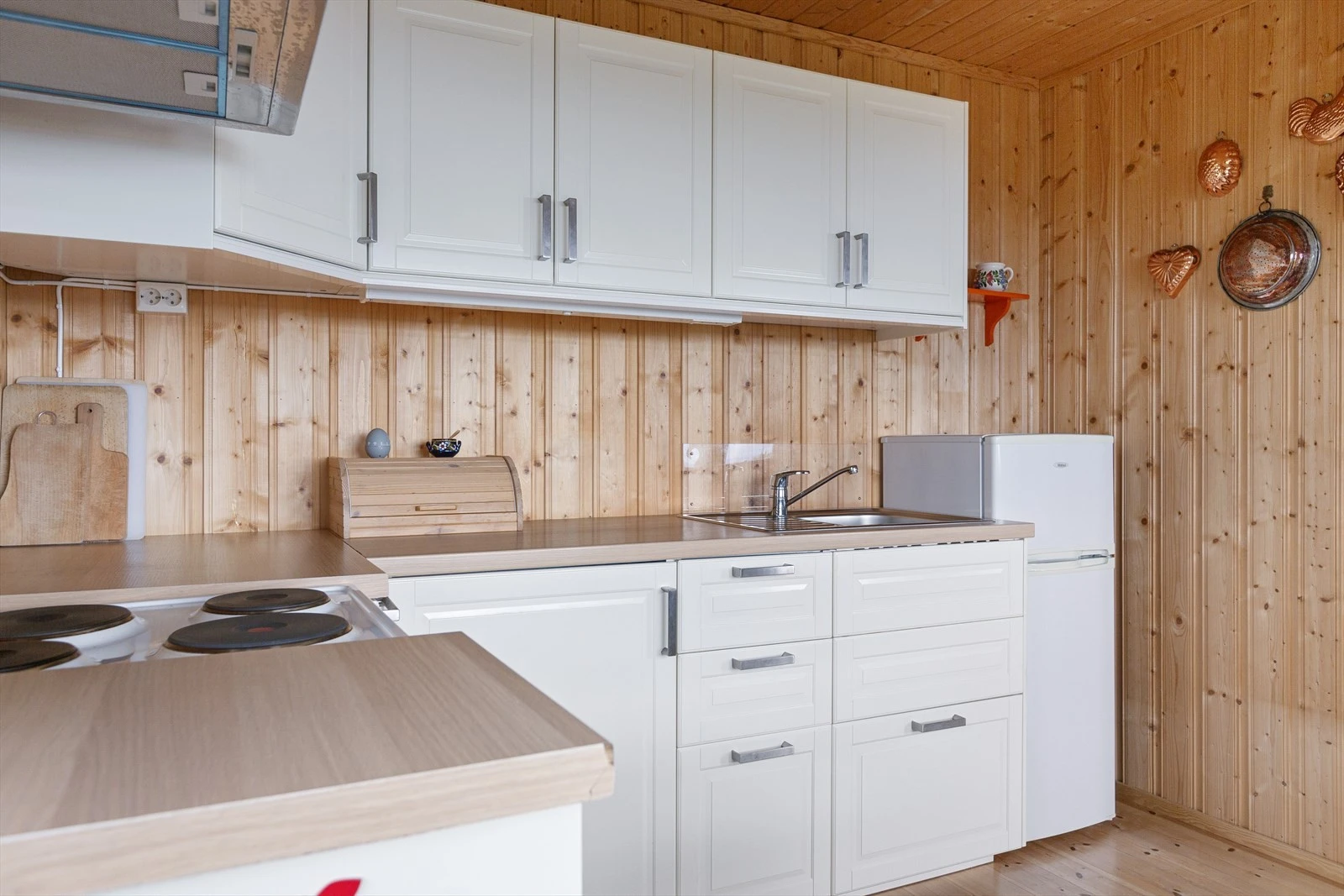 Kjøkkeninnredningen er i malte folierte plater med over-og underskap. Den har laminat benkeplate i trefylling med nedfelt oppvaskkum og kran av stål. Galleribilde