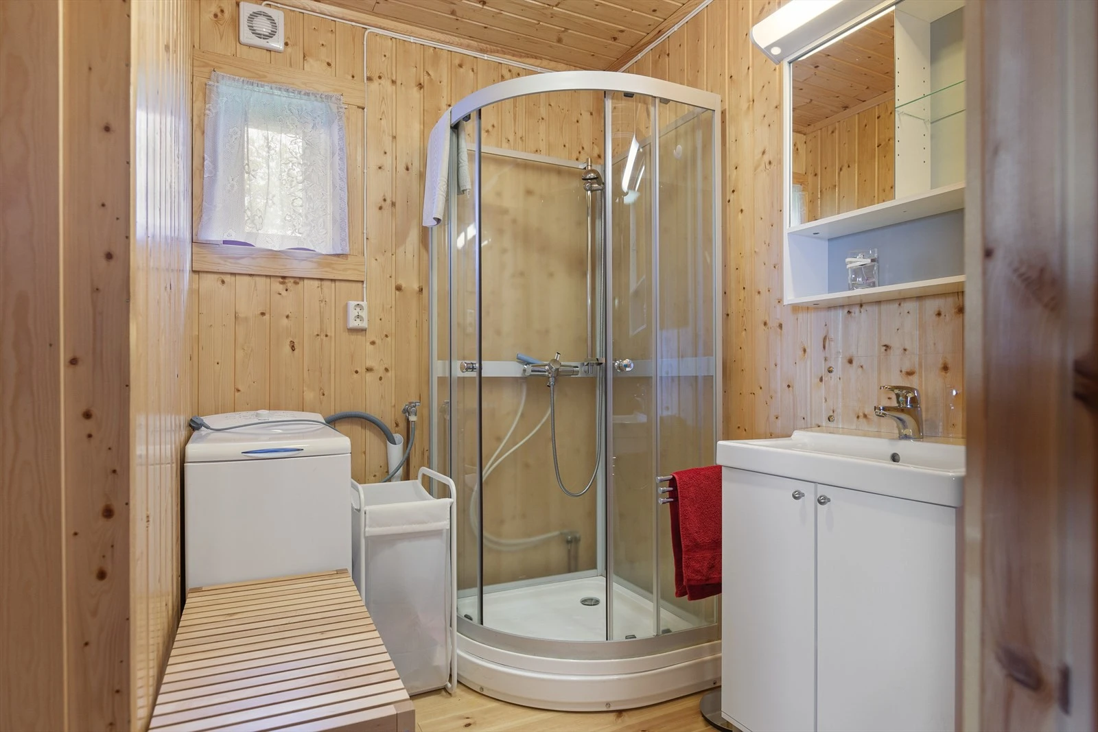 Bad har lakkert gulv i heltre, samt vegger og himling kledd med trepanel. Lys baderomsinnredning i folierte plater med over- og underskap, speil og belysning. Frittstående dusjkabinett og opplegg for vaskemaskin, hvor vaskemaskinen følger med i handelen. Galleribilde