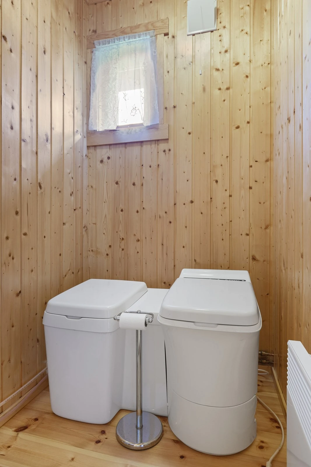 Nær badet er det et eget toalettrom, også dette med lakkert gulv i heltre, vegger og himling er kledd med trepanel. I rommet, som har veggventil i yttervegg, er det montert forbrenningstoalett og urintoalett. Galleribilde