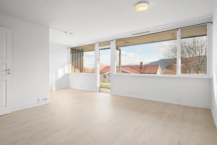 Romslig stue med store vinduer og utgang til uteområde Galleribilde