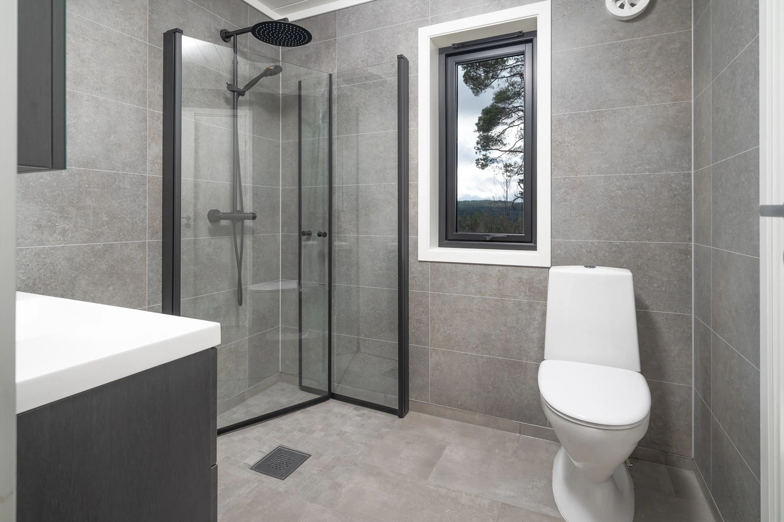 Smakfullt bad med fliser, varmekabler og sorte detaljer Galleribilde