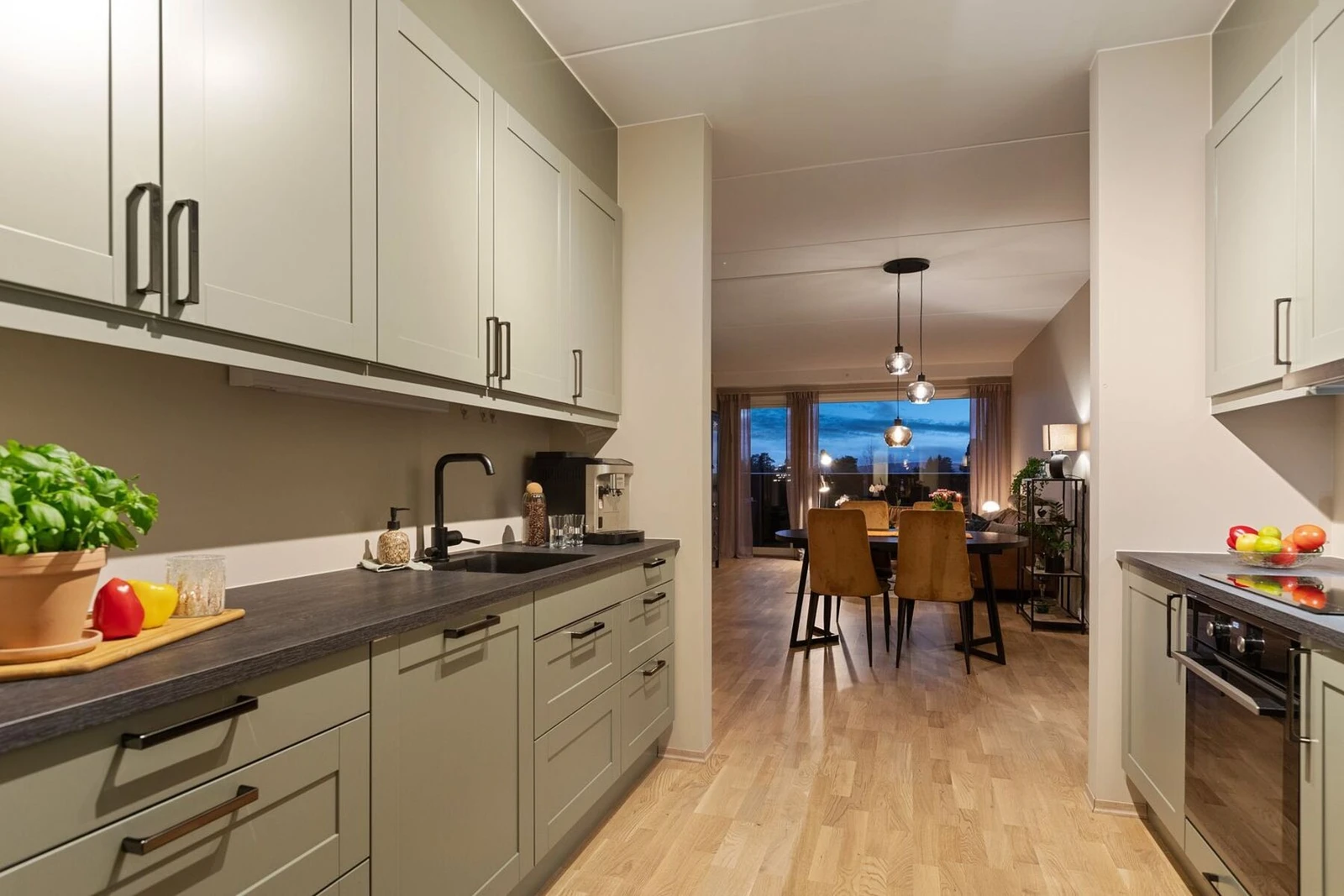 Når kvelden senker seg, skaper belysningen en koselig atmosfære, og utsikten mot stuen og videre ut mot balkongen binder rommene sammen på en elegant måte. Galleribilde