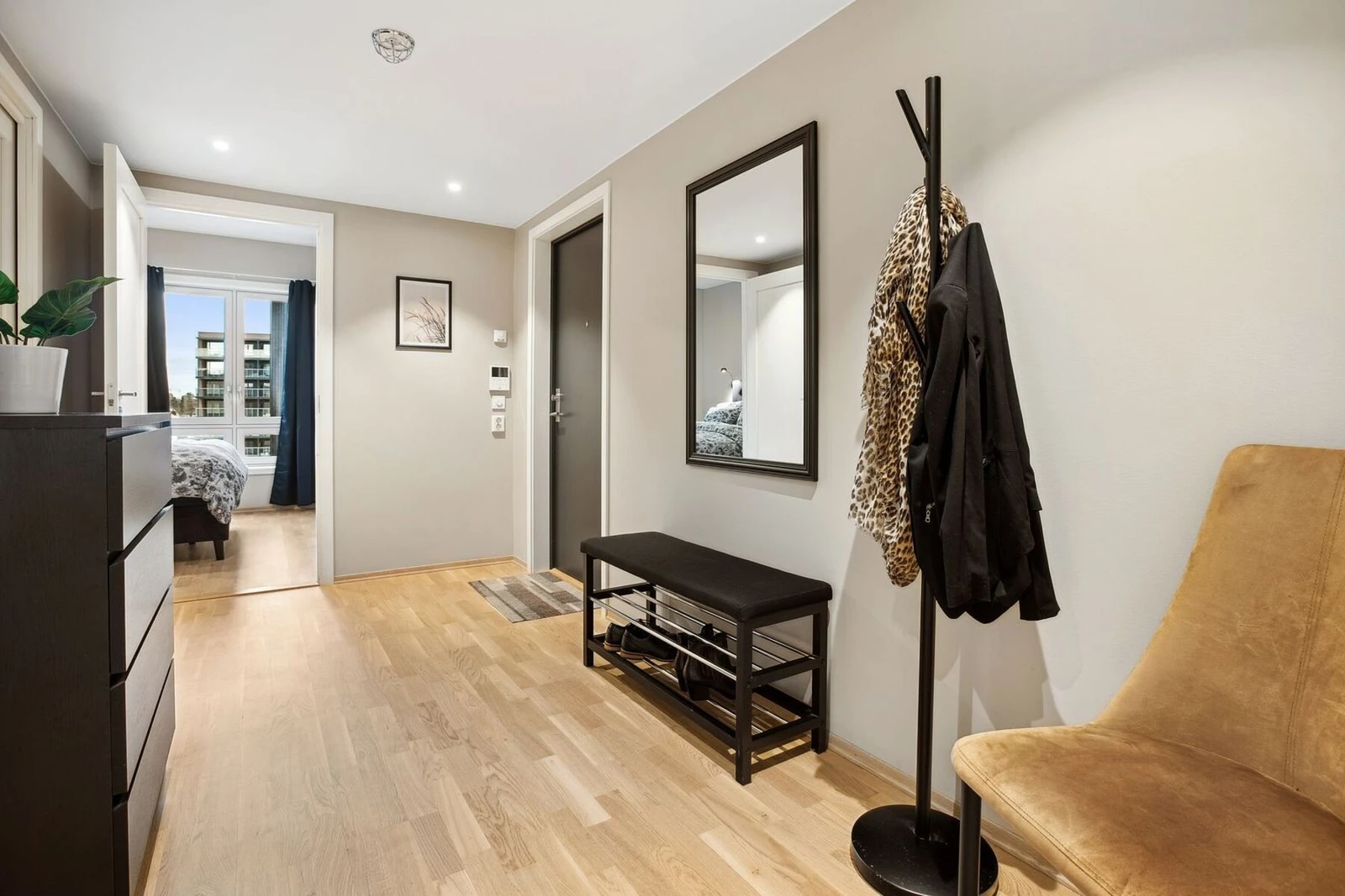 Entreen setter tonen for resten av leiligheten med sitt moderne uttrykk og smarte løsninger. Den mørke inngangsdøren skaper en stilig kontrast til de lyse veggene og gulvet, samtidig som den bidrar til et innbydende førsteinntrykk. Galleribilde