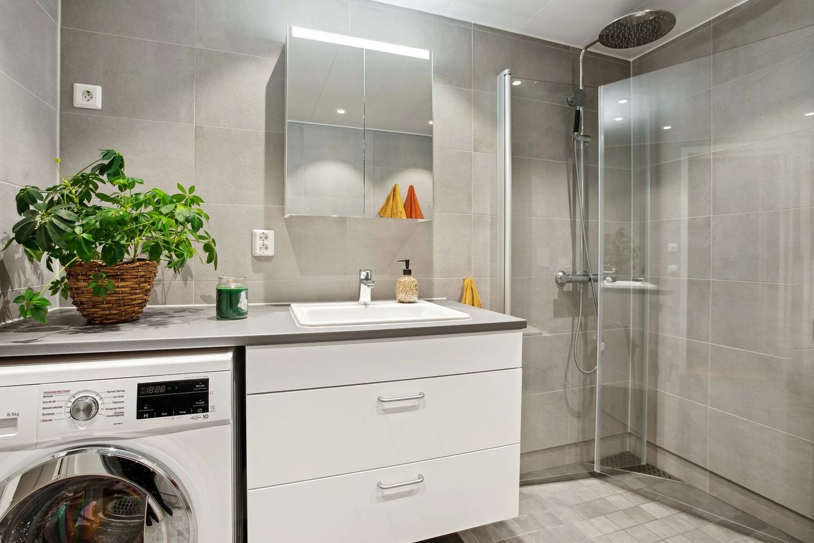 Videre kommer vi inn til dette elegante badet som kombinerer funksjonalitet med moderne estetikk. Med sine store grå fliser og integrerte dusjnisje er rommet både praktisk og stilfullt.v Galleribilde