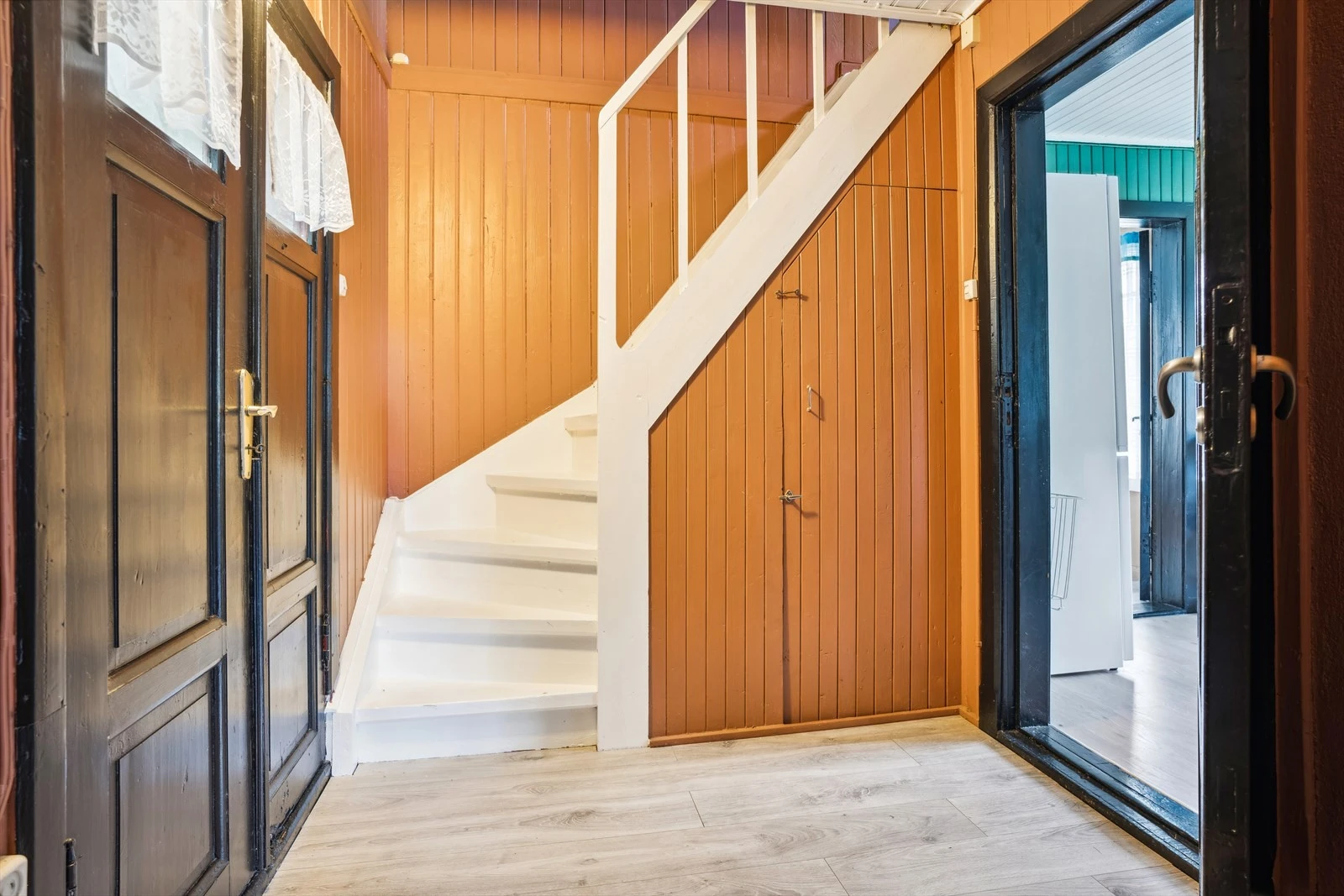 Entré med trapp som knytter boligens etasjer sammen, døra under trappa går ned til råkjeller. Galleribilde