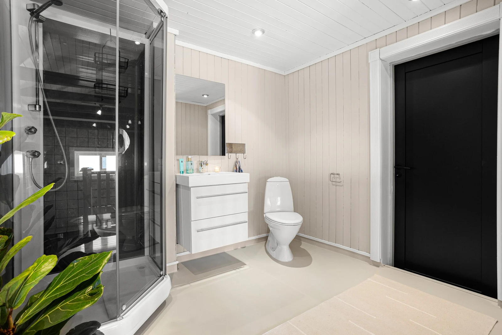 Bad i 1. etg med gulvmontert toalett, innredning med speil på vegg og dusjnisje Galleribilde