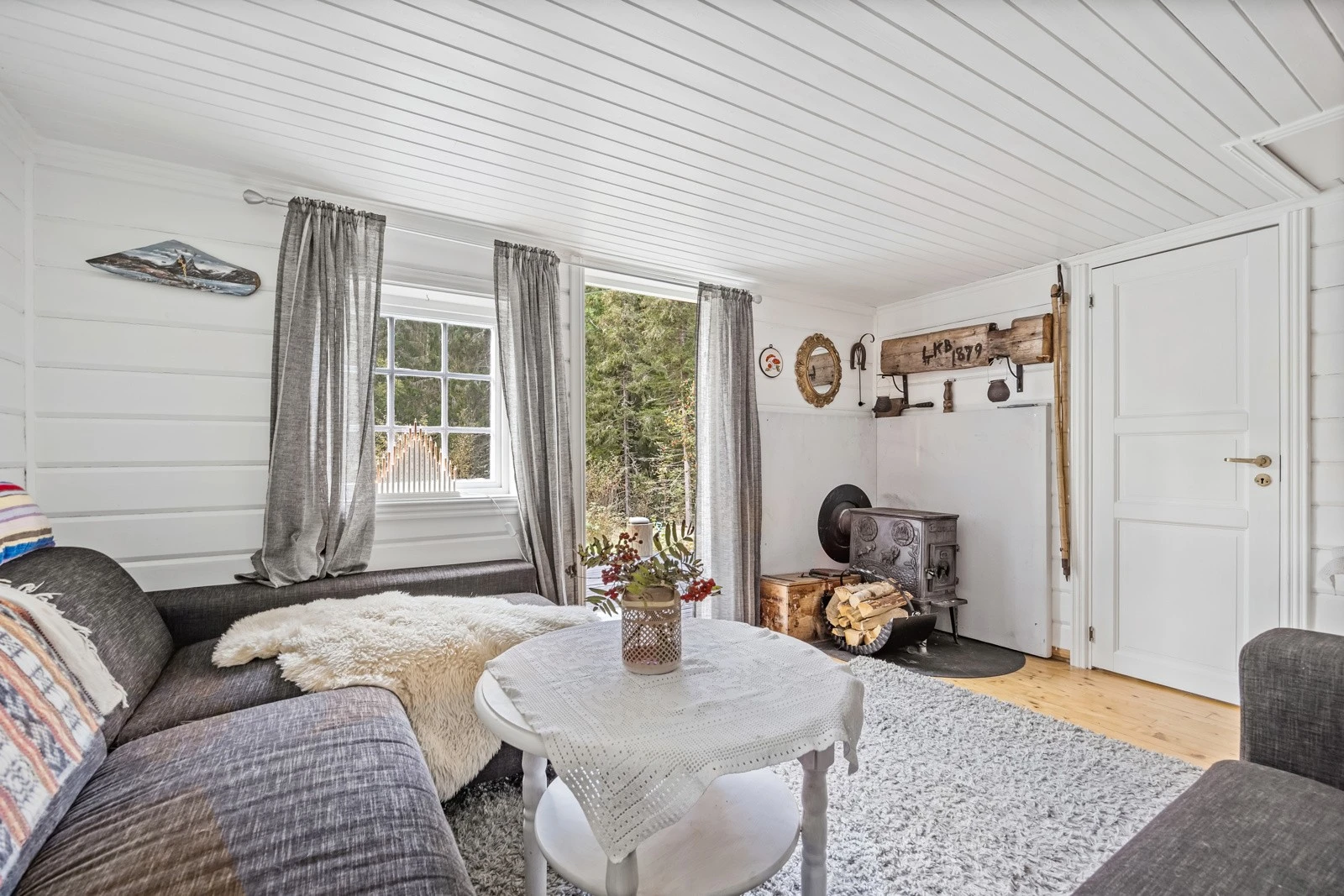 Hjemmekoselig atmosfære med peisovn, myke tekstiler og store vinduer som slipper inn naturlig lys fra de naturskjønne omgivelsene. Galleribilde