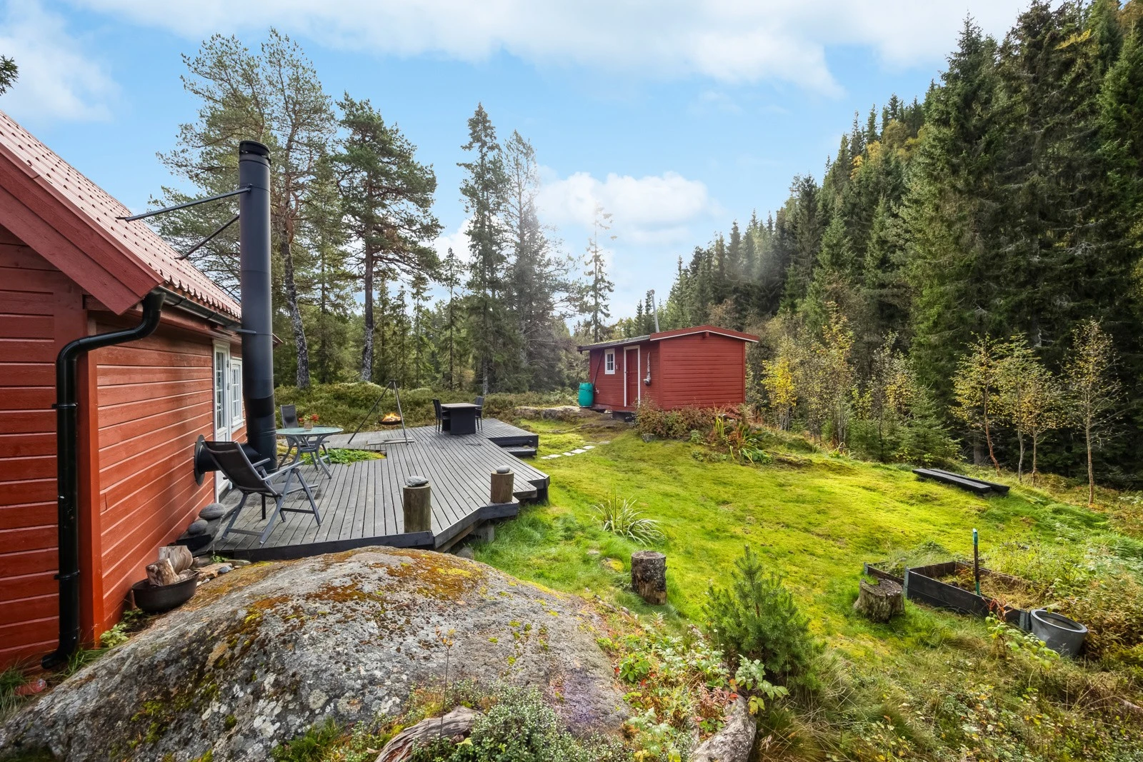 Romslig terrasse med plass til avslapning, omkranset av frodig natur og skog som skaper en rolig atmosfære. Galleribilde