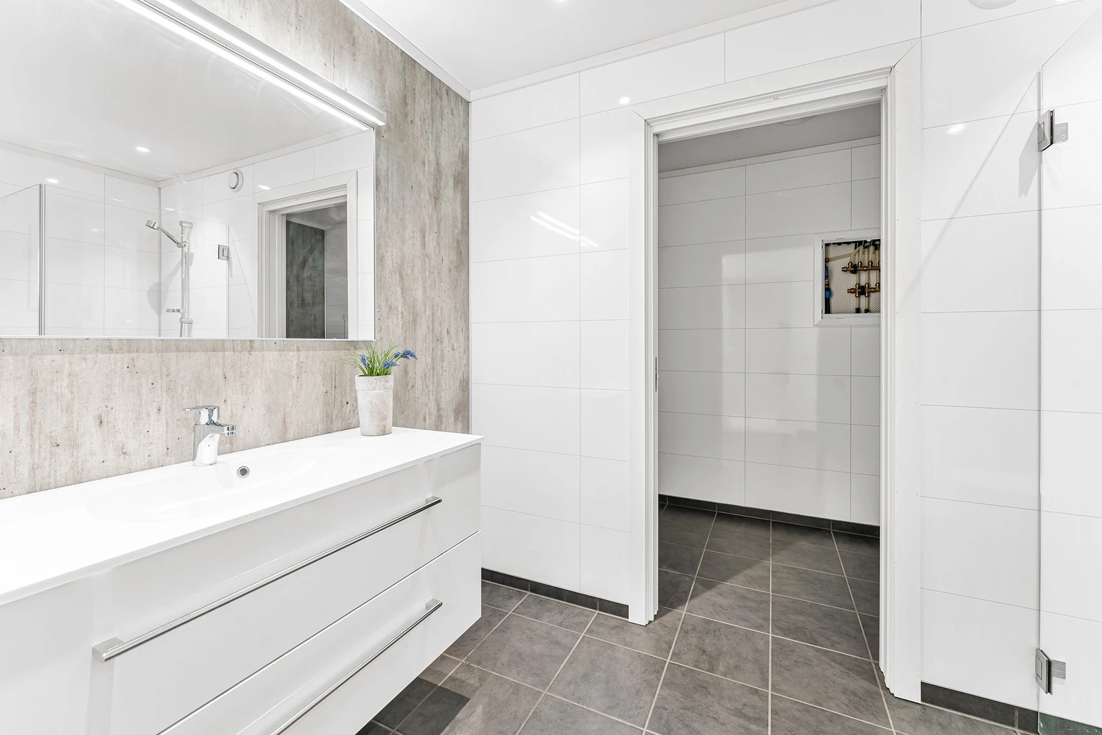 Badet er lyst og fint og har flislagt gulv og våtromsplater på vegger. Eget rom innenfor for vaskemaskin. Galleribilde