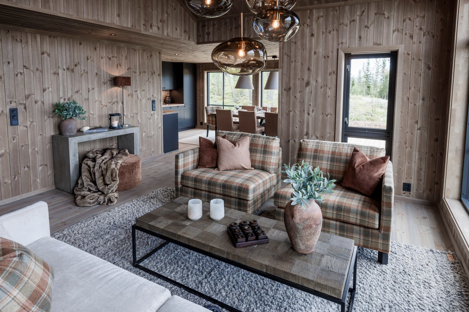 Hytta har et sosialt oppholdsrom med delvis åpen stue-, spisestue- og kjøkkenløsning Galleribilde