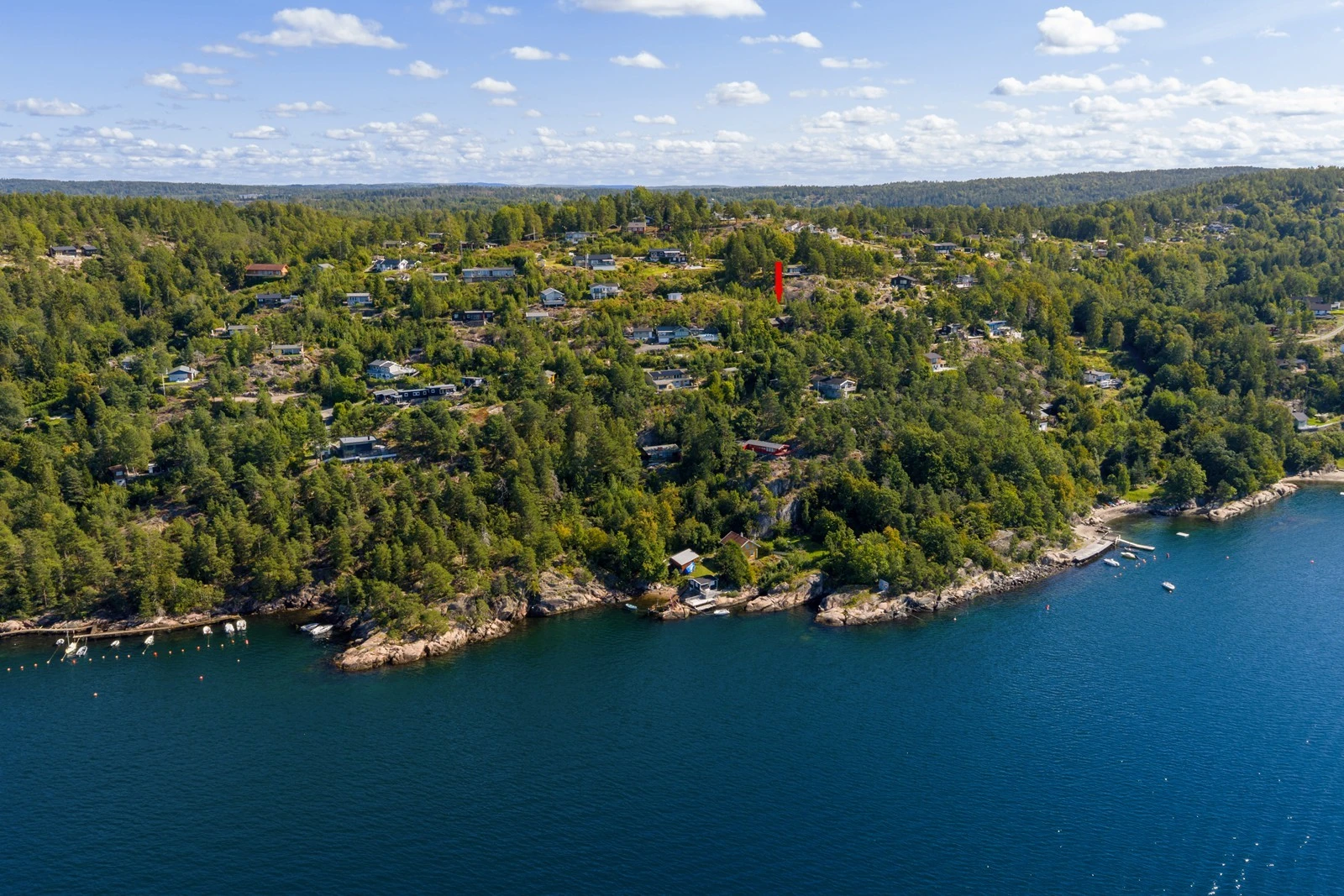 Eiendommen ligger vestvendt og solrikt til på en høyde med flotte utsiktsforhold mot fjorden (markert med rød pil) Galleribilde