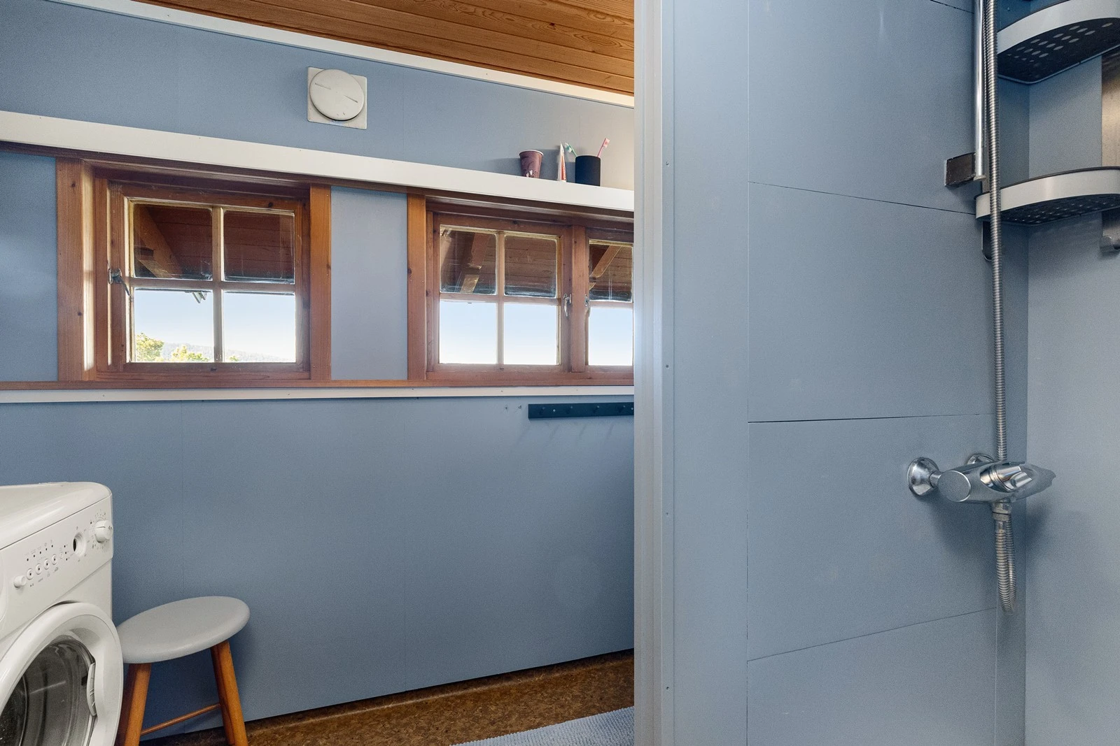 Dusjbad utstyrt med baderomsinnredning med servant, speil og lys. Dusjnisje med dusjkar og forheng Galleribilde