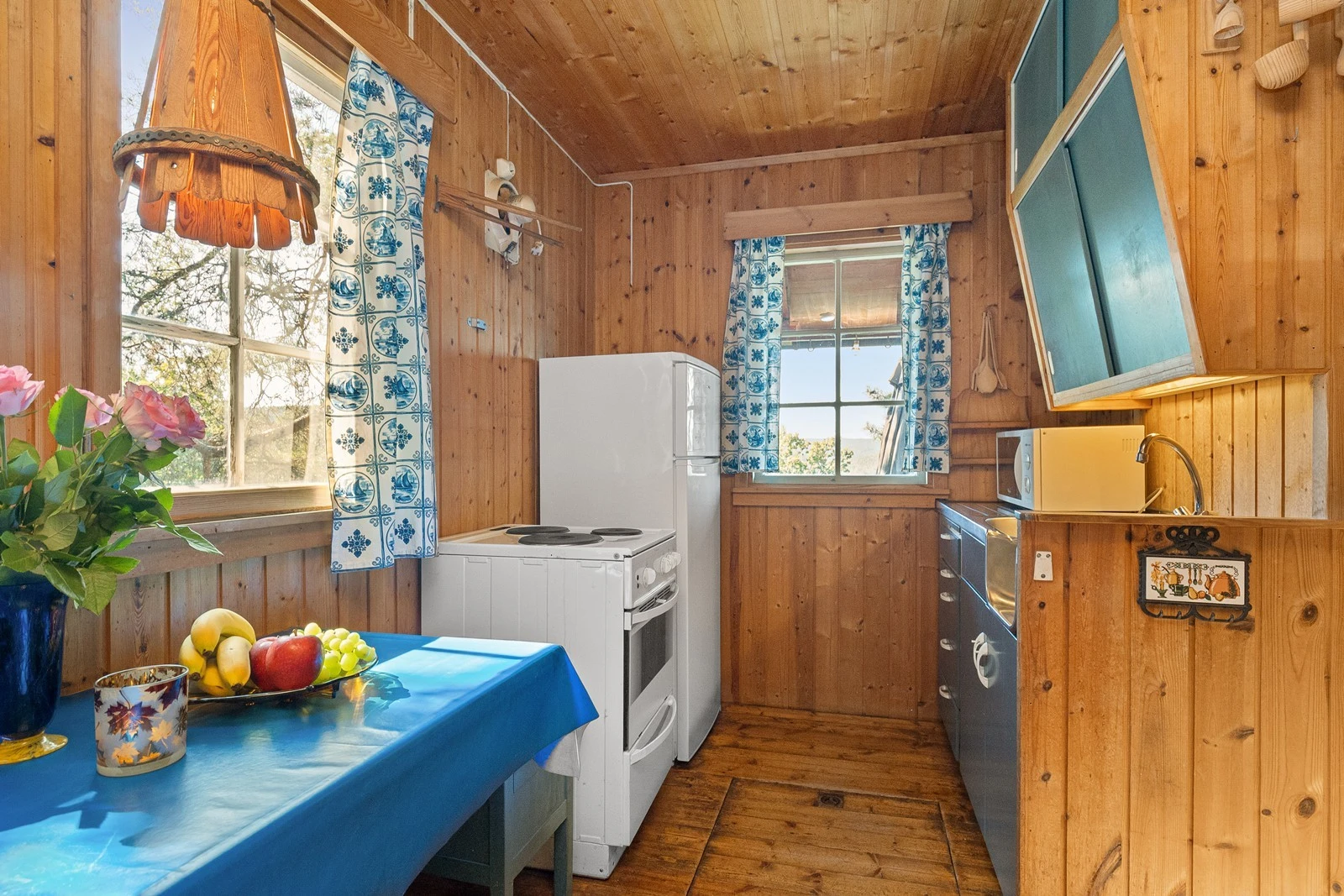 Kjøkken med original kjøkkeninnredning med malte skap, og skuffefronter med lys under overskap og benkebeslag med utslagsvask. Frittstående hvitevarer som avtrekksvifte med utlufting på yttervegg Galleribilde