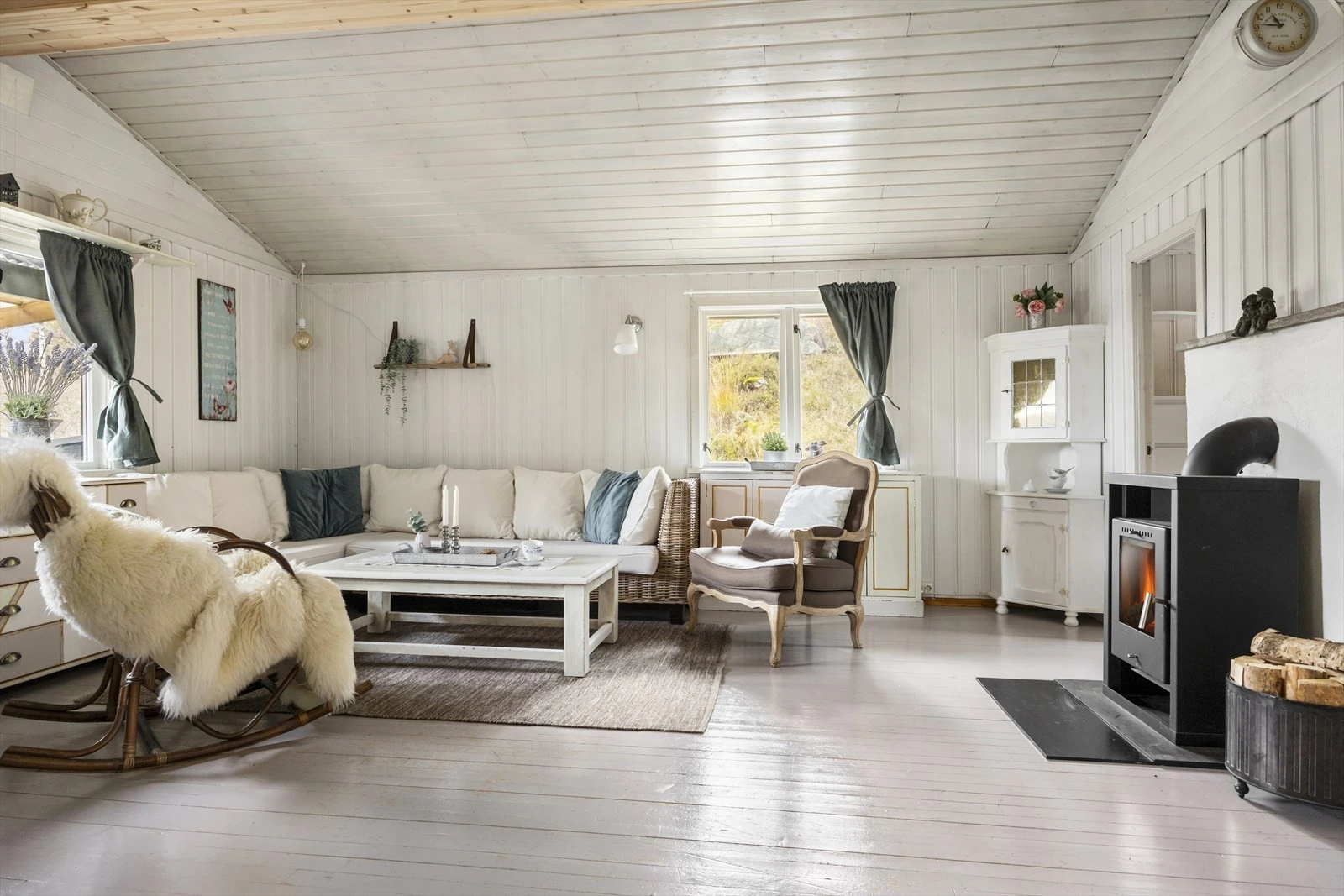 Den lyse og romslige stuen har plass til både sittegruppe og spisebord. Ekstra takhøyde gir en god romfølelse og store vinduer slipper inn rikelig med naturlig lys. Den nye peisovnen fra 2015 gir både varme og en hyggelig atmosfære på kalde dager. Galleribilde