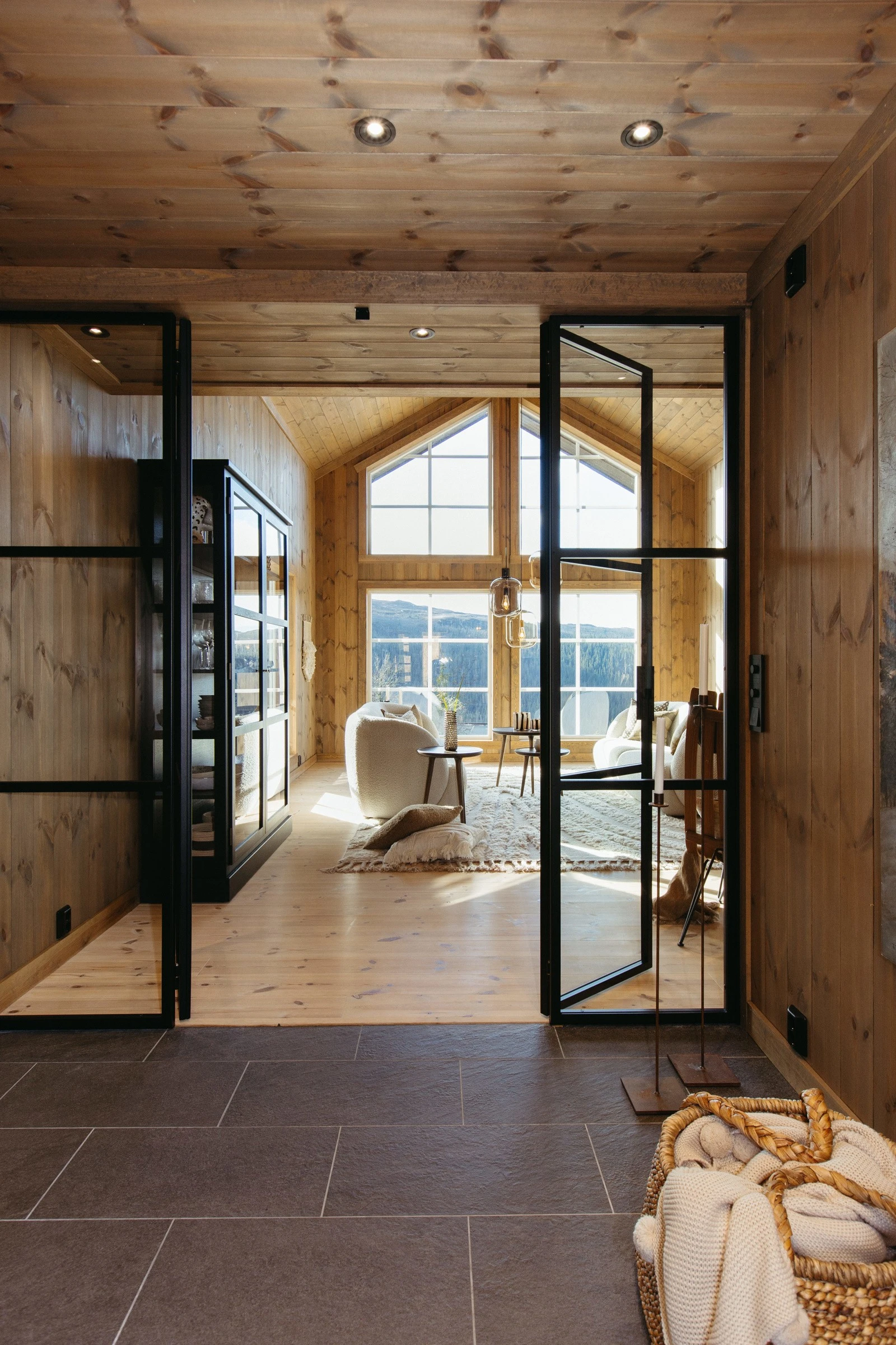 Hall og stue/kjøkken adskilt med glassvegg og dører i smijern fra den lokale produsenten Myhre Smie gir hytten et ekslusivt uttrykk. Galleribilde