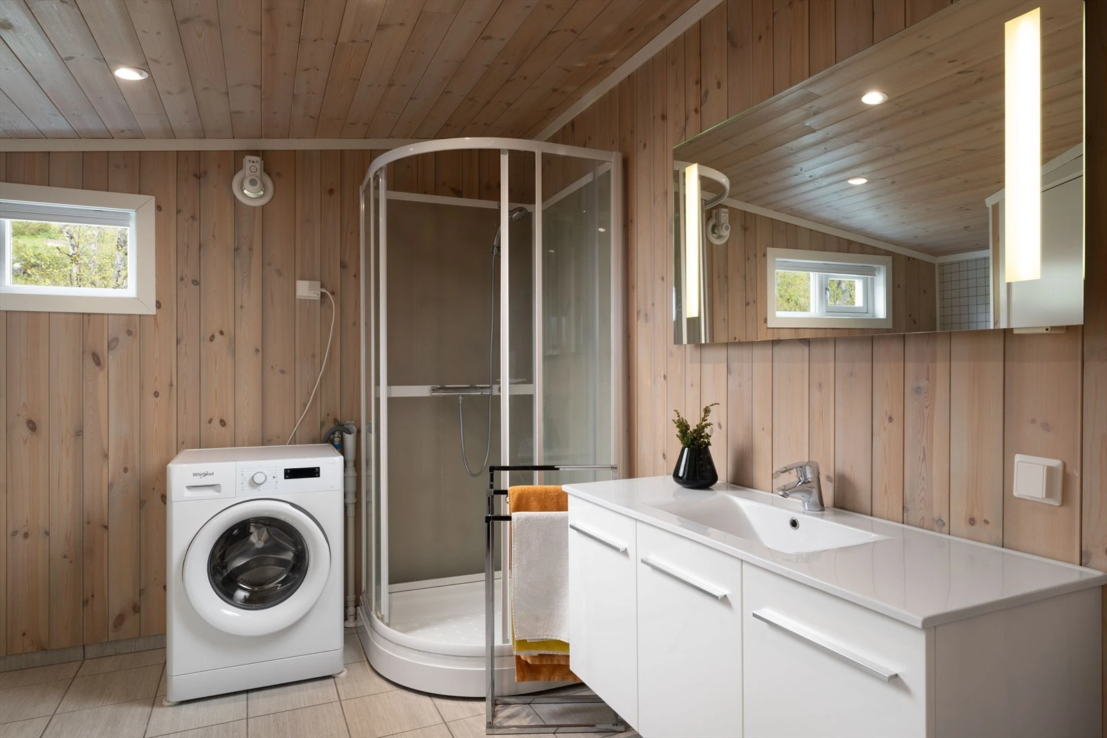 Badet har panel på vegger og i himling. Flislagt gulv med varmekabel. Rommet er innredet med baderomsinnredning med servant,
vegghengt toalett, dusjkabinett og opplegg for vaskemaskin. Galleribilde