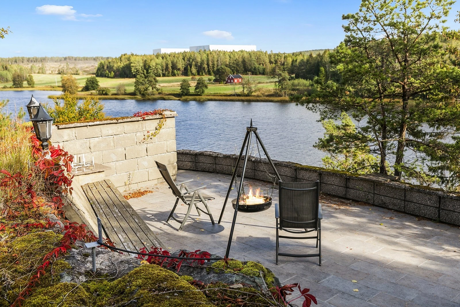 En trapp fører ned til en flislagt uteplass på 40 kvm med integrert sittebenk - et lunt og skjermet område som innbyr til ro og avslapning Galleribilde