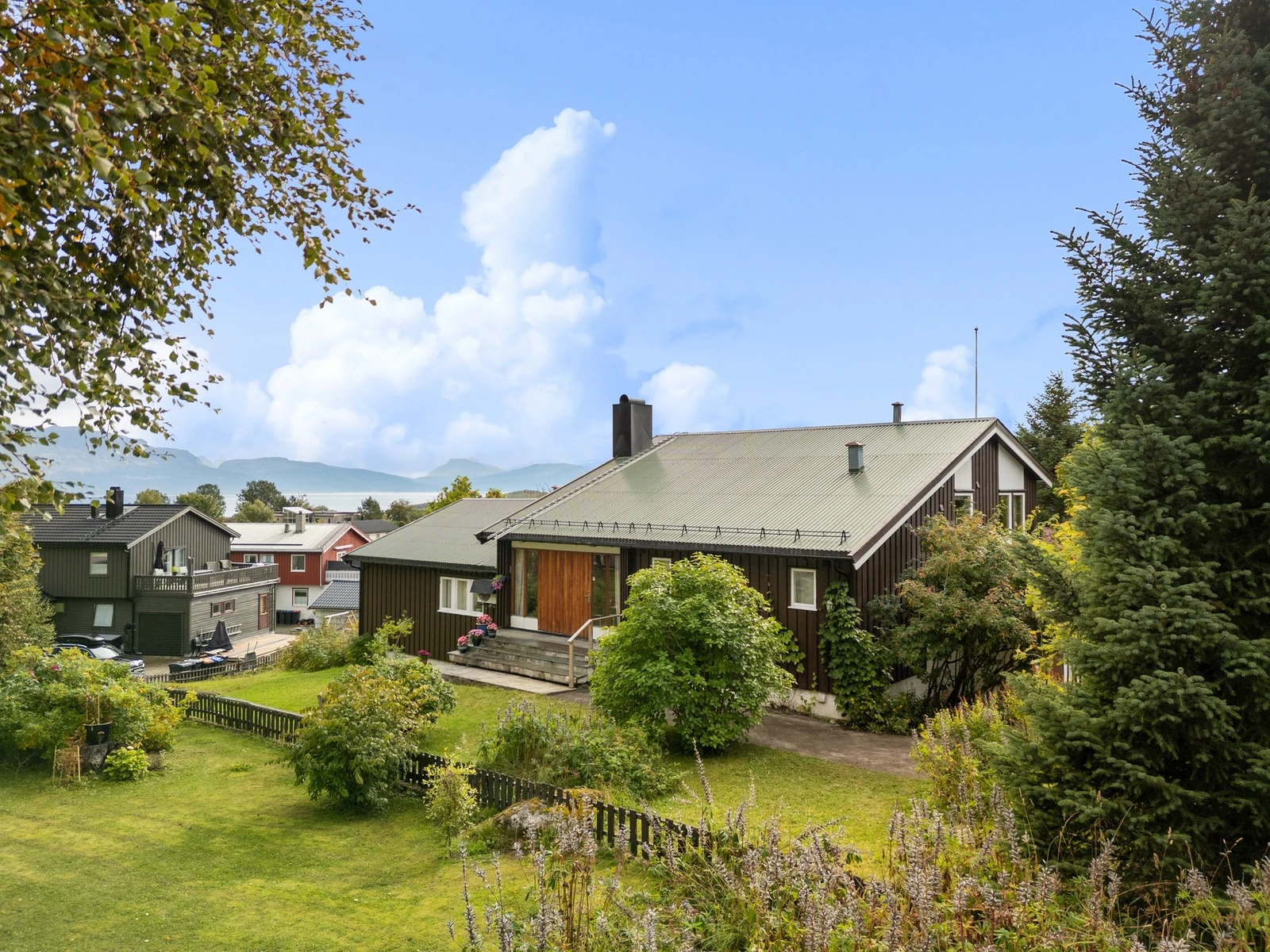 Pent oppbygd inngangsparti og velstelte hageområder med blomster og beplantning Galleribilde