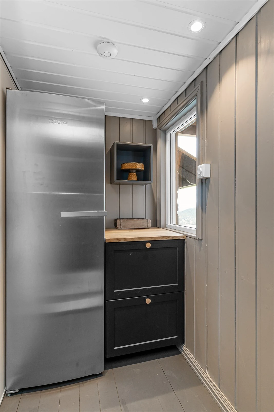 Det gamle inngangspartiet har blitt integrert som et ekstra rom til kjøkkenet. Her med stort kjøleskap og ekstra benkinnredning. Galleribilde