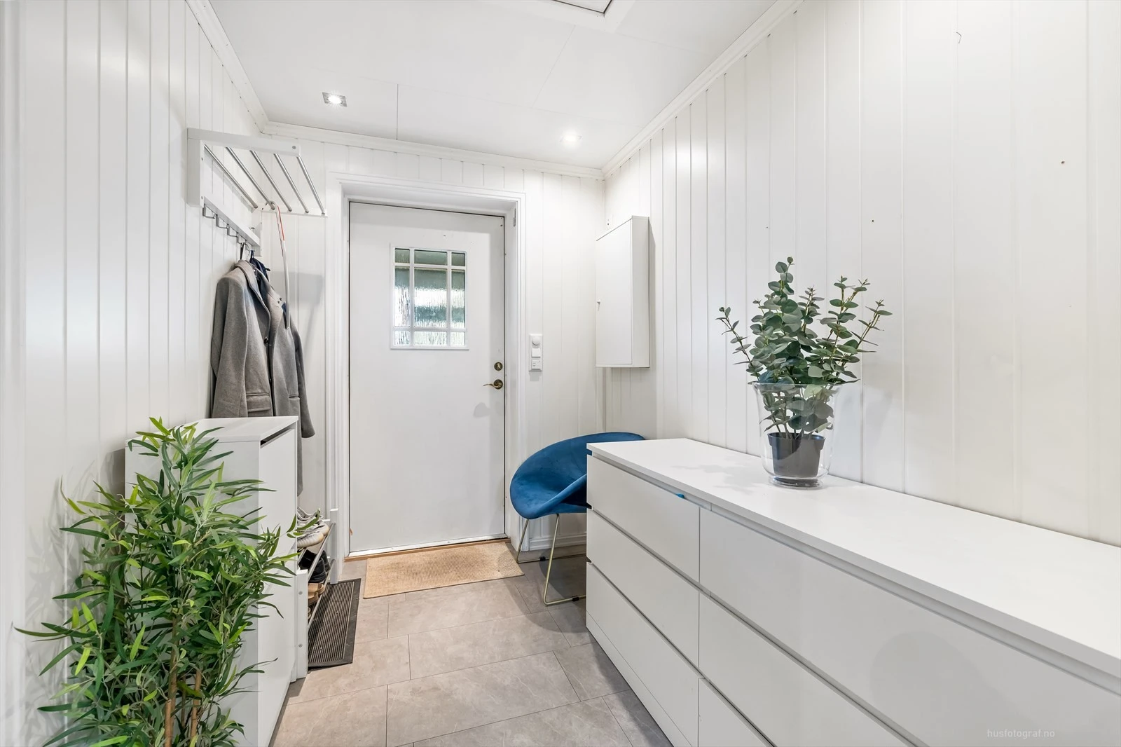 Lys og innbydende entré med moderne oppbevaringsløsninger og plass til sittemøbel.
