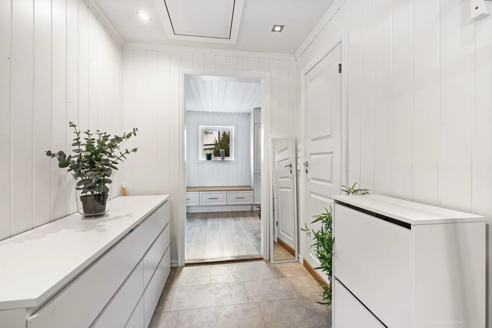 Lys og innbydende entré med moderne oppbevaringsløsninger og delikate, lyse overflater.