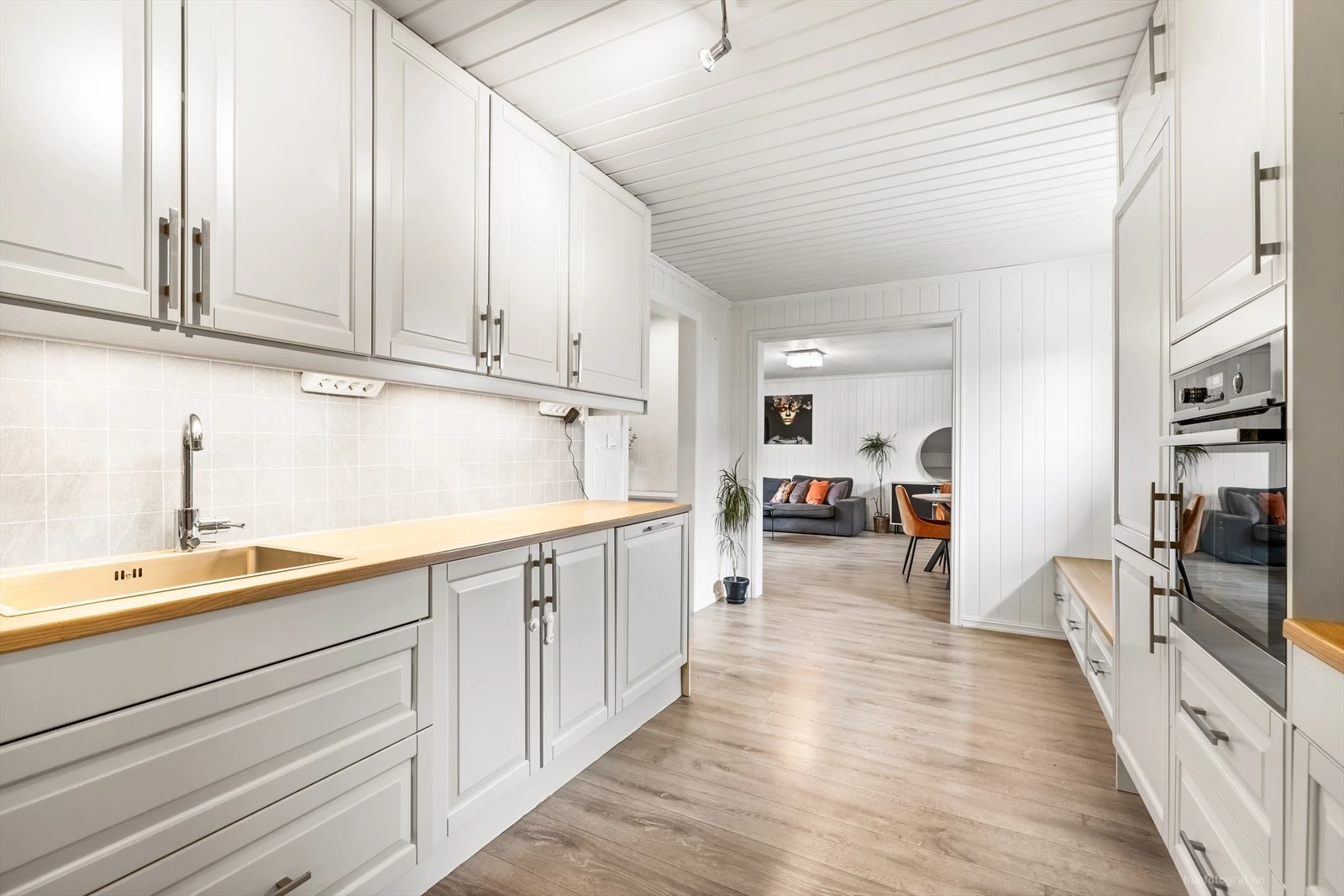 Moderne kjøkken med integrerte hvitevarer og åpen løsning mot stue.