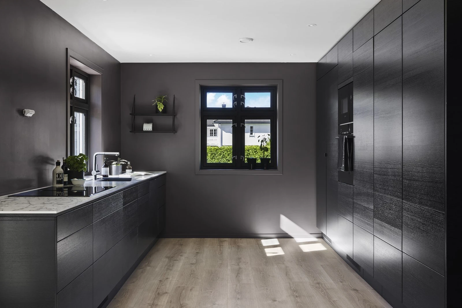 Stilren og moderne innredning, nytt i 2024, med slette sorte fronter på underskap, skuffer og høyskap Galleribilde
