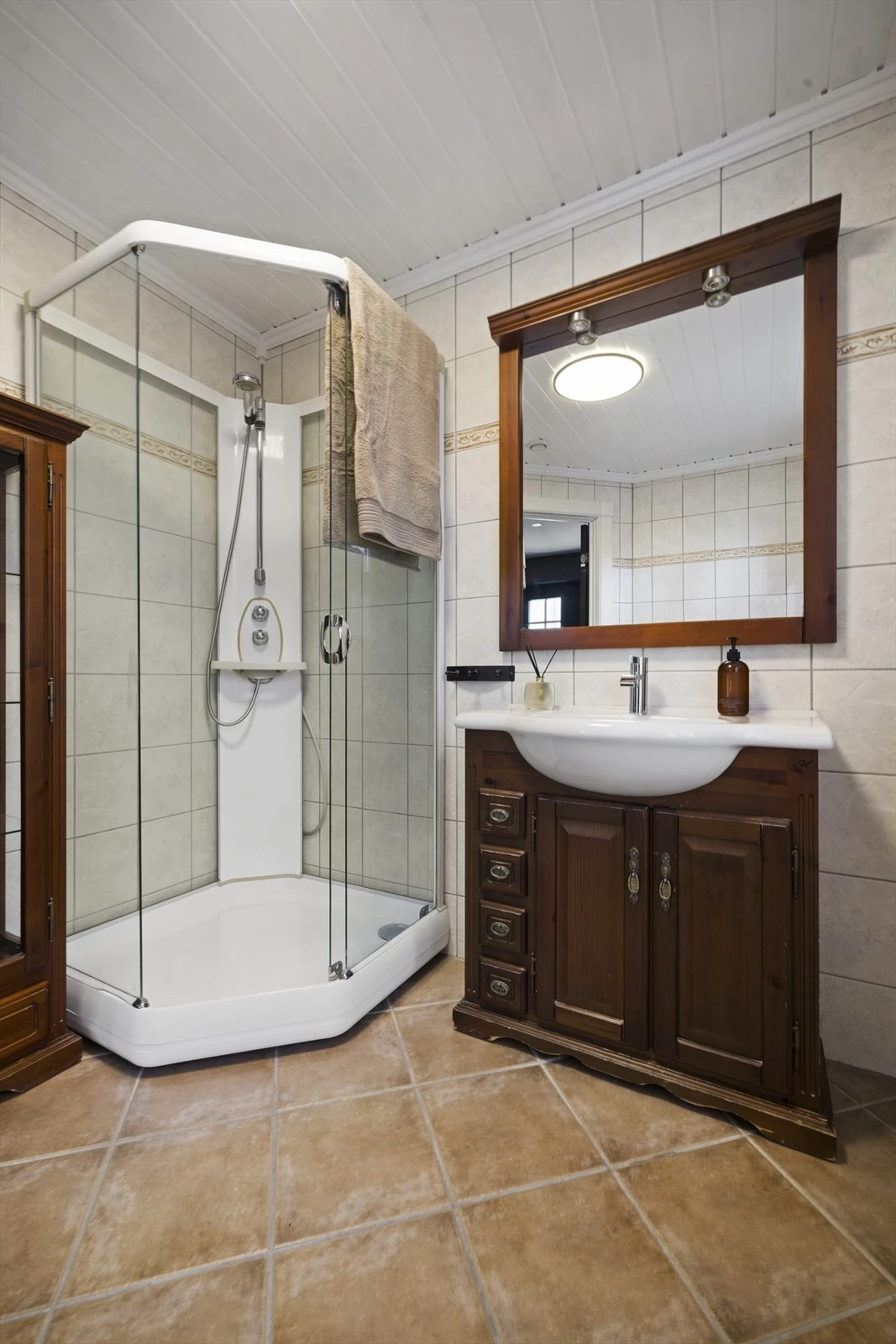 Baderomsinnredning med skuffer og skap, samt heldekkende servantplate. Tilhørende speil med belysning. Badekar, dusjkabinett og gulvstående toalett Galleribilde