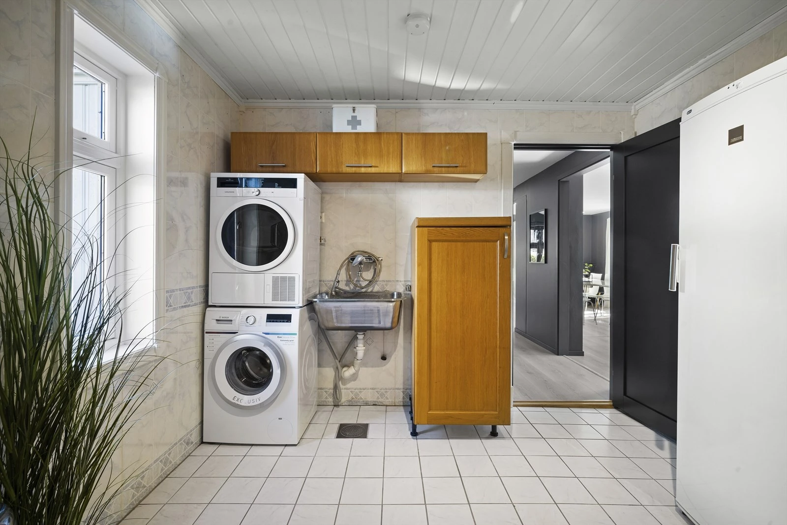 Vaskerom av god størrelse med opplegg til vaskemaskin og tørketrommel med utslagsvask. God plass til skap og oppbevaring Galleribilde