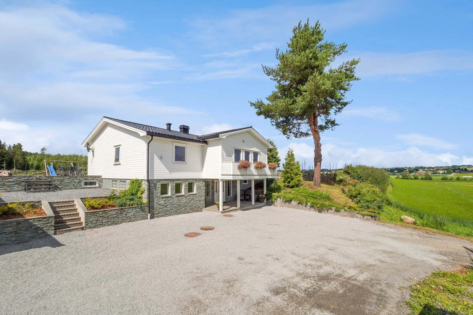 Eiendommen har stor gruset gårdsplass og dobbelgarasje Galleribilde