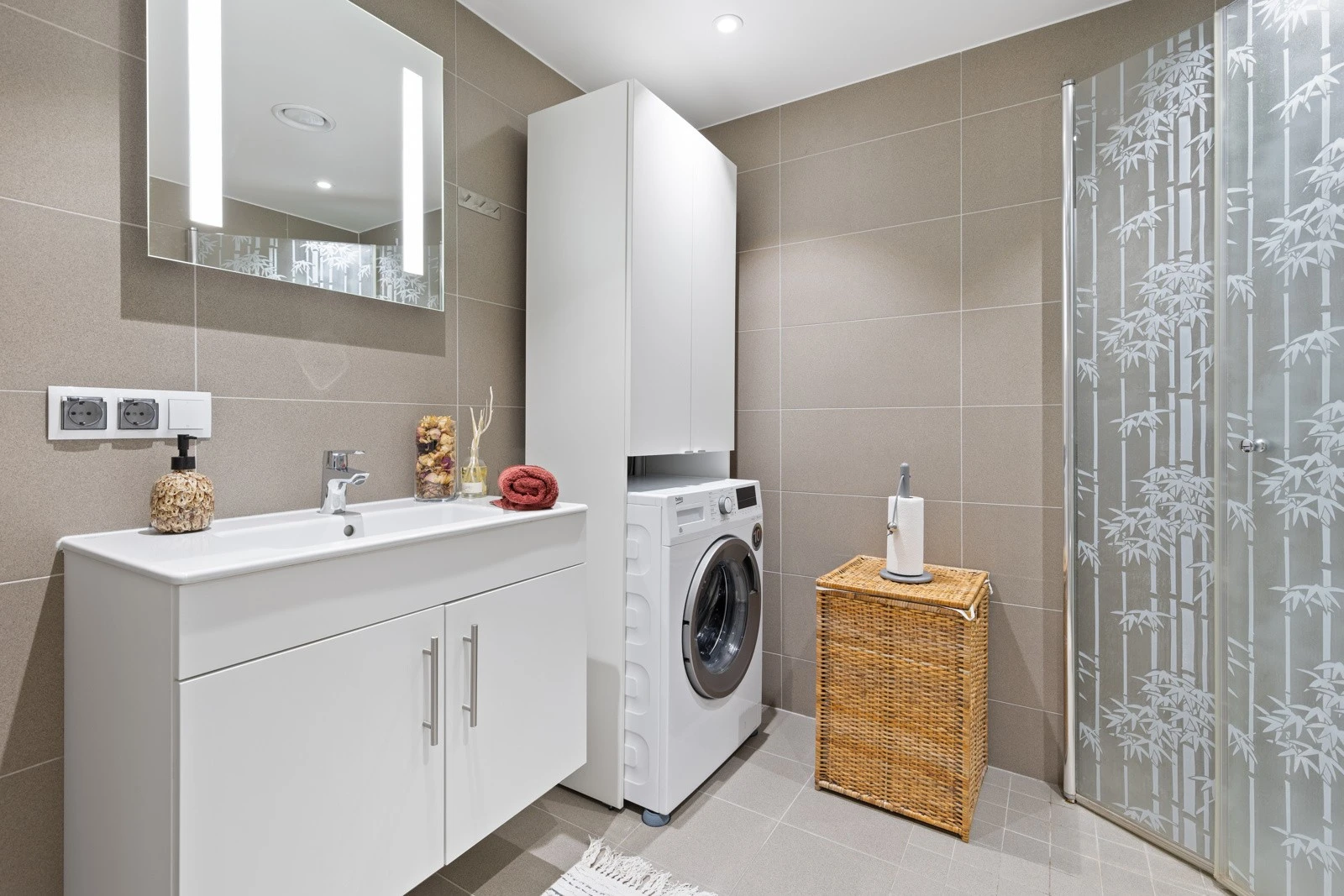 Smakfullt bad med flislagte overflater og vannbåren varme i gulv. Innredningen består av moderne skapinnredning med heldekkende hvit blank vask og vegghengt speil med integrert LED lys. Videre er det vegghengt toalett i hvitt porselen med dempesete. Galleribilde