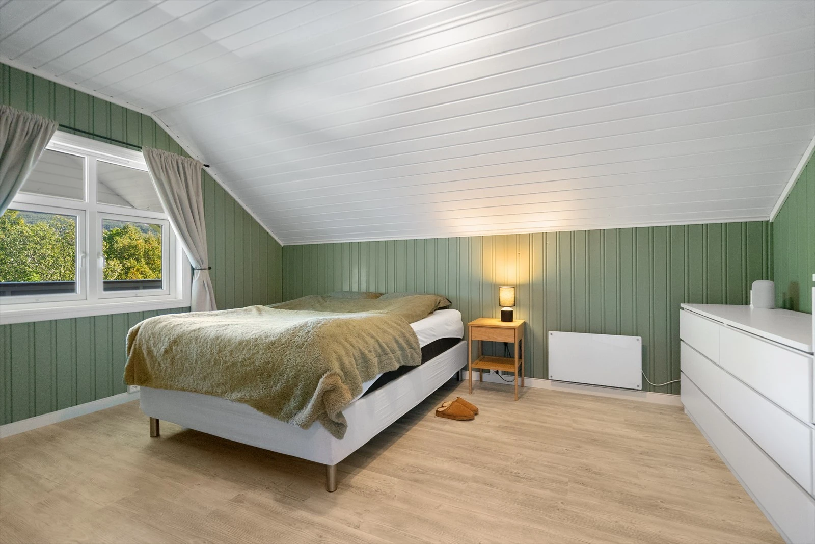 Romslig soverom med skråtak og store vinduer som gir godt lysinnslipp Galleribilde