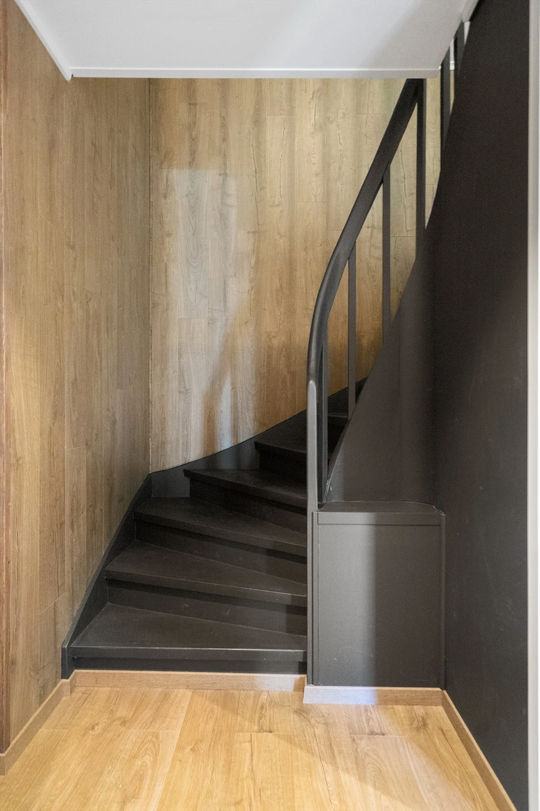 Stilfull trappoppgang fra 1.etasje til 2.etasje - sort trapp med eikedetaljer på veggene Galleribilde