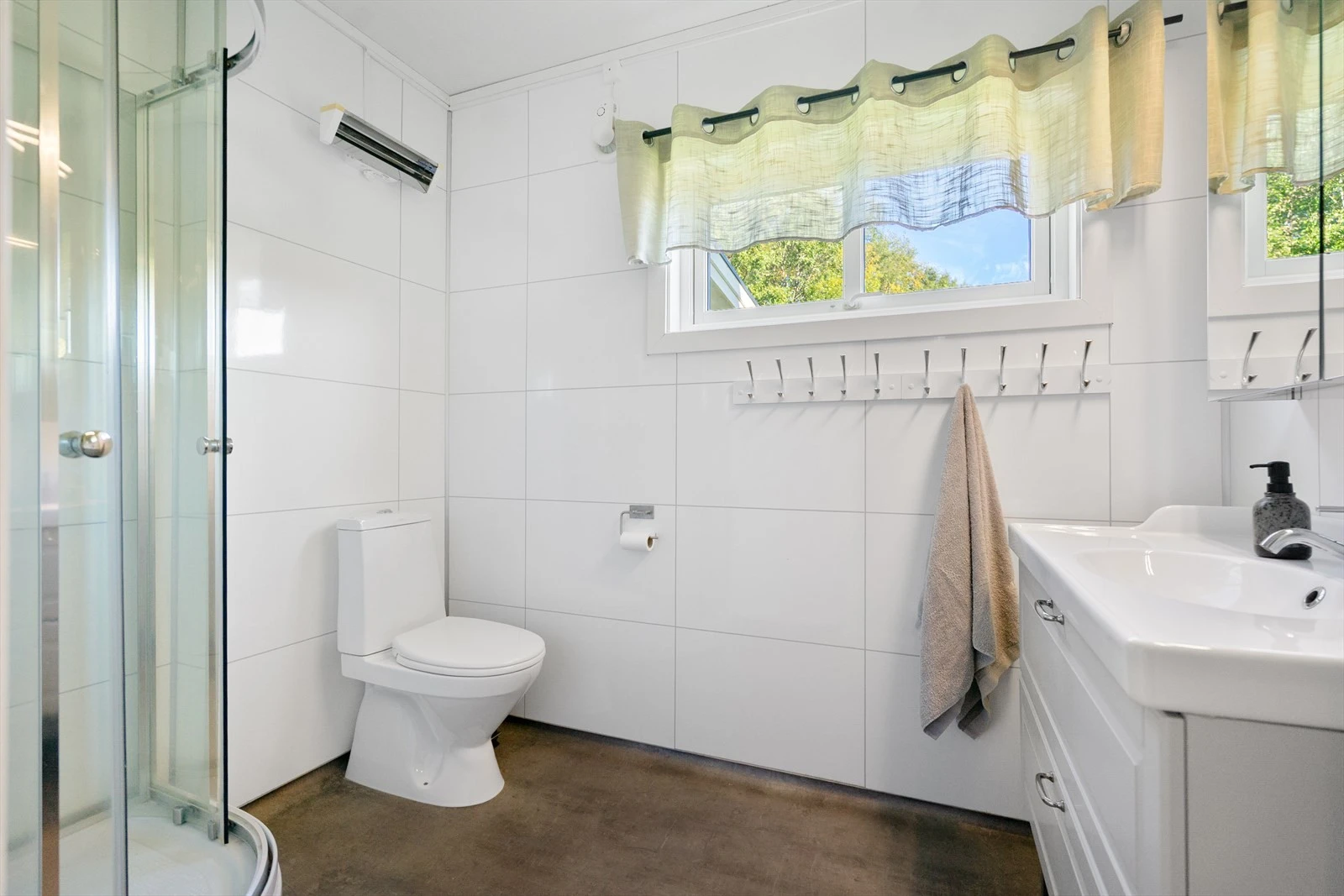 Lyst og moderne bad med dusjhjørne, toalett og varme i gulv - en praktisk løsning for hele familien Galleribilde