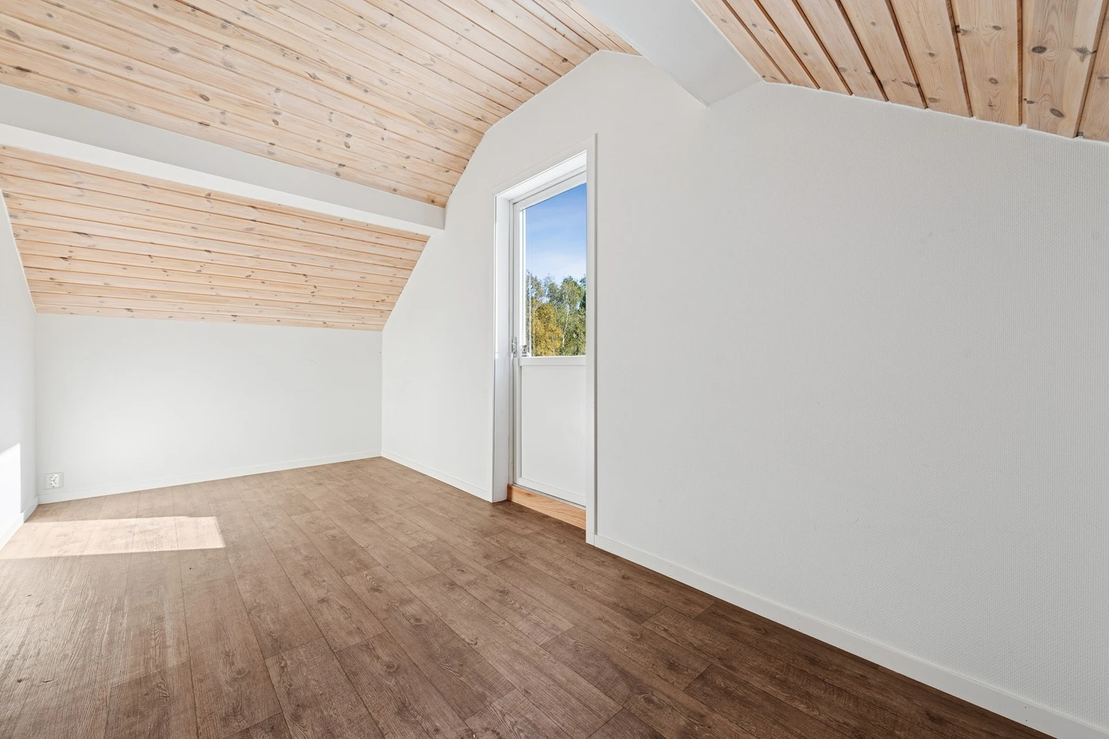 Det andre soverommet i etasjen har lyse vegger og skråtak med panel, som gir en lun atmosfære. Rommet har også utgang til en liten balkong! Et hyggelig sted å trekke ut for frisk luft. Galleribilde