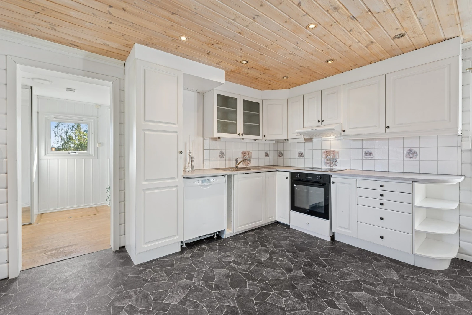 Kjøkkenet har en innredning med profilerte fronter og laminert benkeplate, kombinert med fliser på vegg. Galleribilde